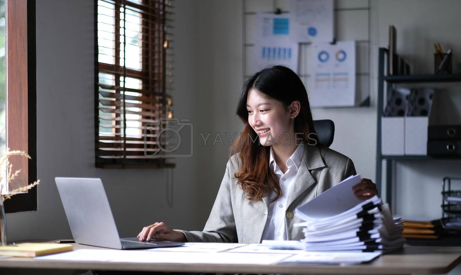 Royalty free image of Charming asian businesswoman sitting working on laptop in office. by wichayada