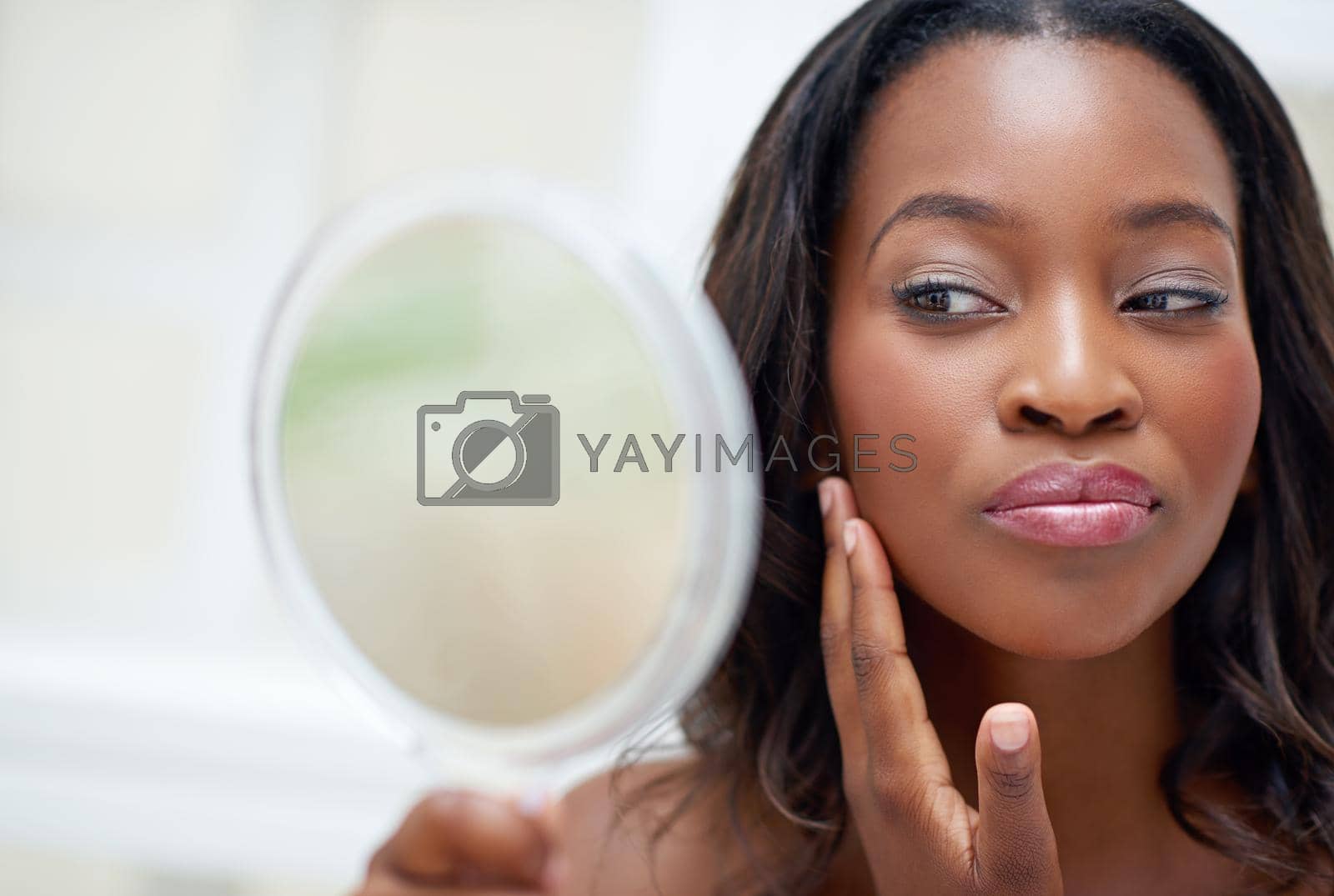 Royalty free image of Looking good. a beautiful young woman looking at herself in small mirror. by YuriArcurs