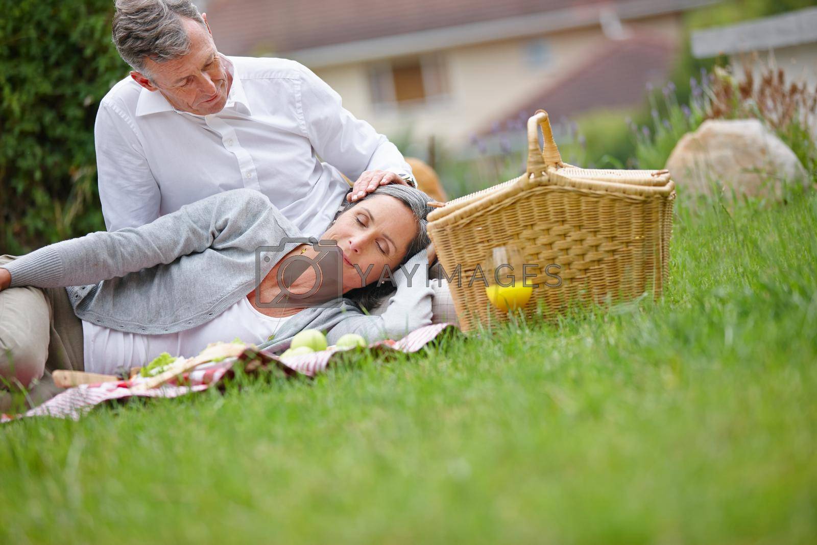 Royalty free image of Blissful moments together. a loving mature couple having a picnic on the grass. by YuriArcurs