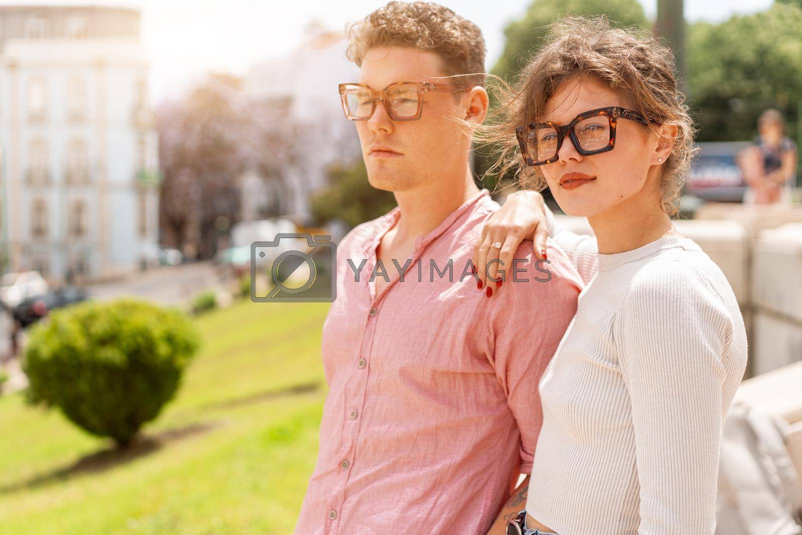 Royalty free image of Young beautiful hipster couple in sunglasses in love walking on old city street by andreonegin