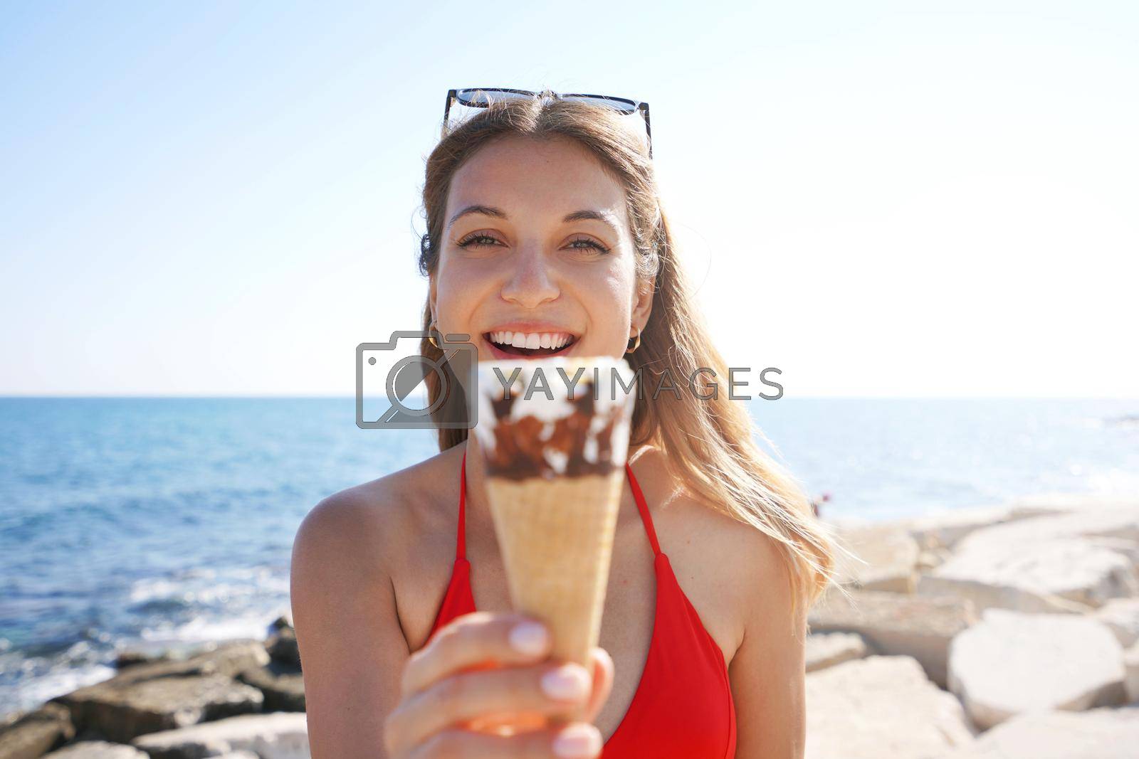 Royalty free image of Close-up of beautiful bikini woman holding ice cream cone italian gelato looking to the camera on the beach on summer by sergio_monti