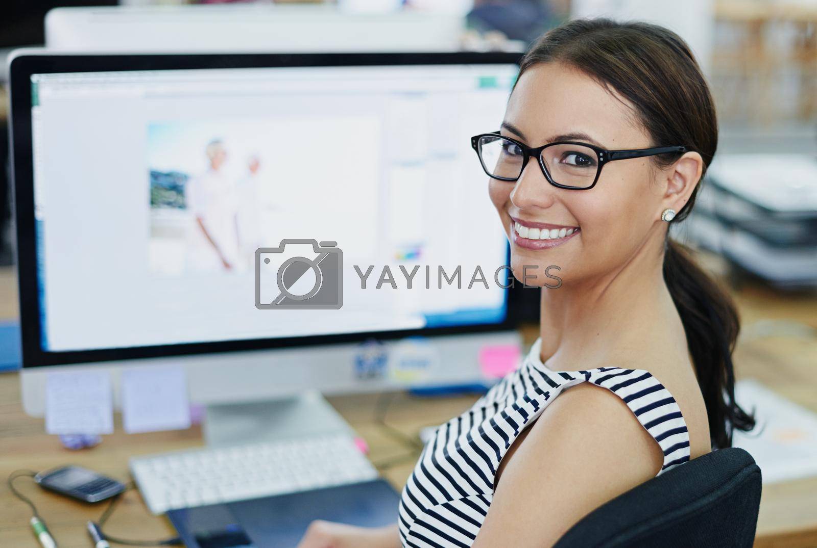 Royalty free image of Success in progress. Portrait of an smiling young designer sitting at a computer in an office. by YuriArcurs