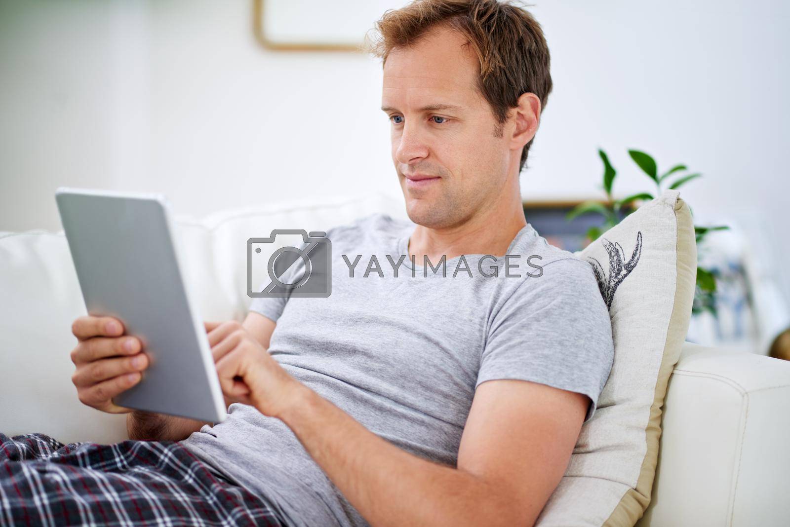 Royalty free image of Weekend browser. a handsome man using his digital tablet at home. by YuriArcurs