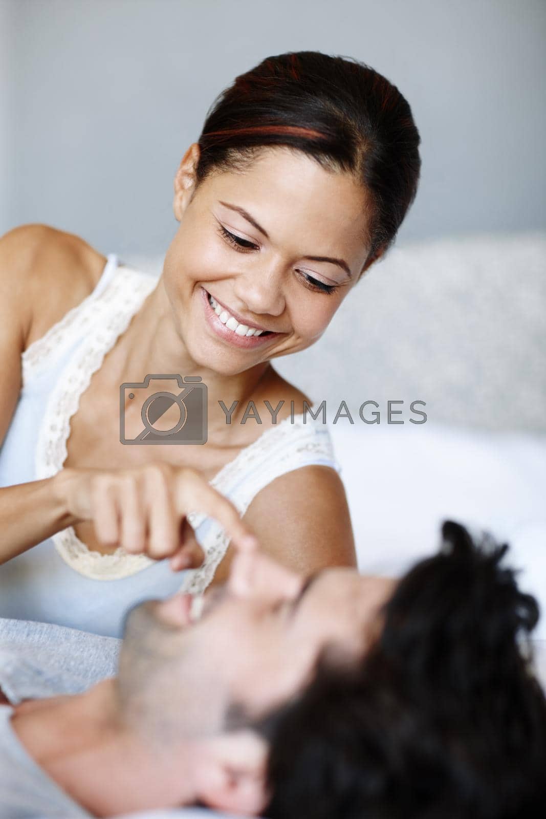 Royalty free image of Wakey wakey. Playful woman lying alongside her boyfriend in bed. by YuriArcurs