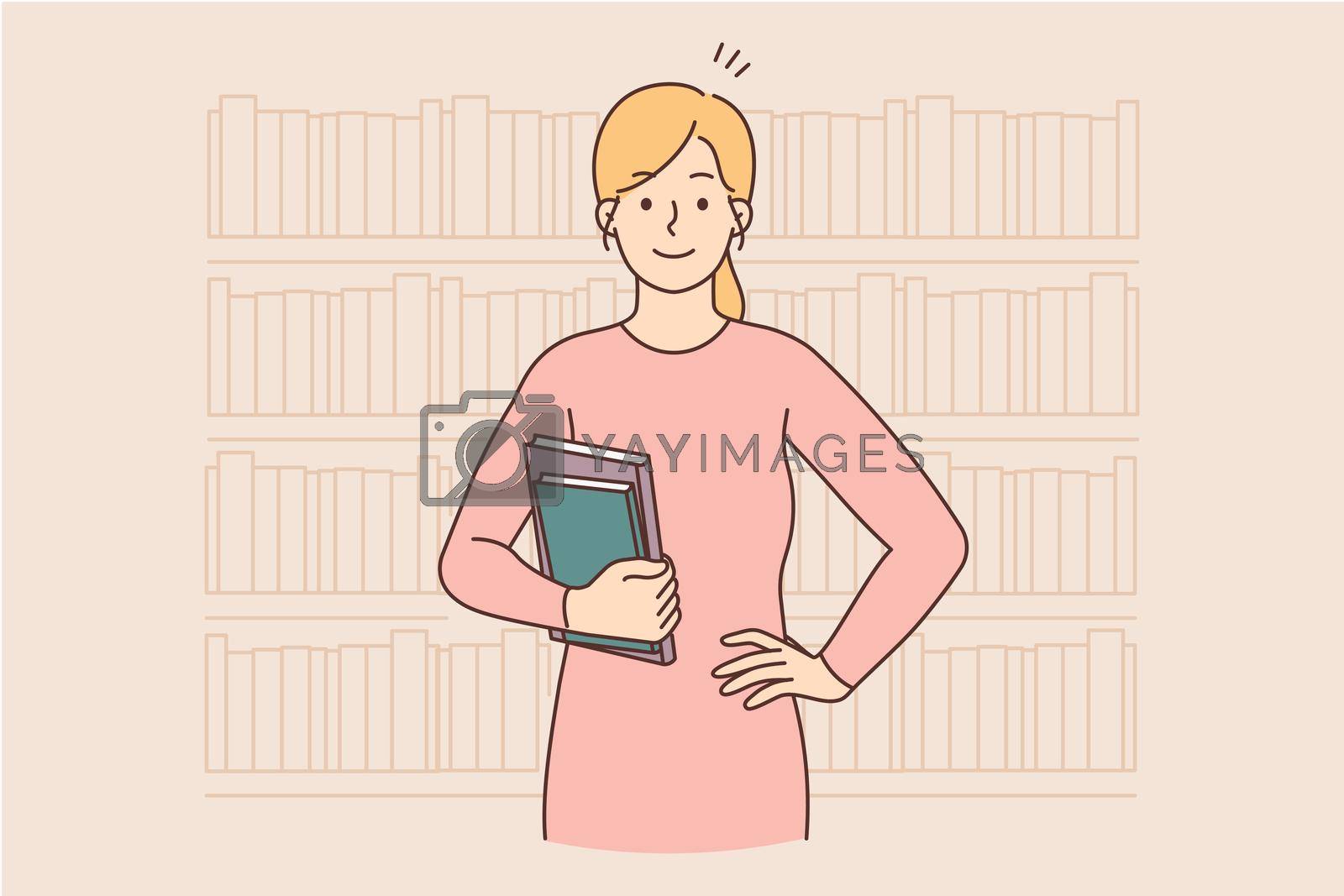 Royalty free image of Smiling woman holding books standing in library by Vasilyeu