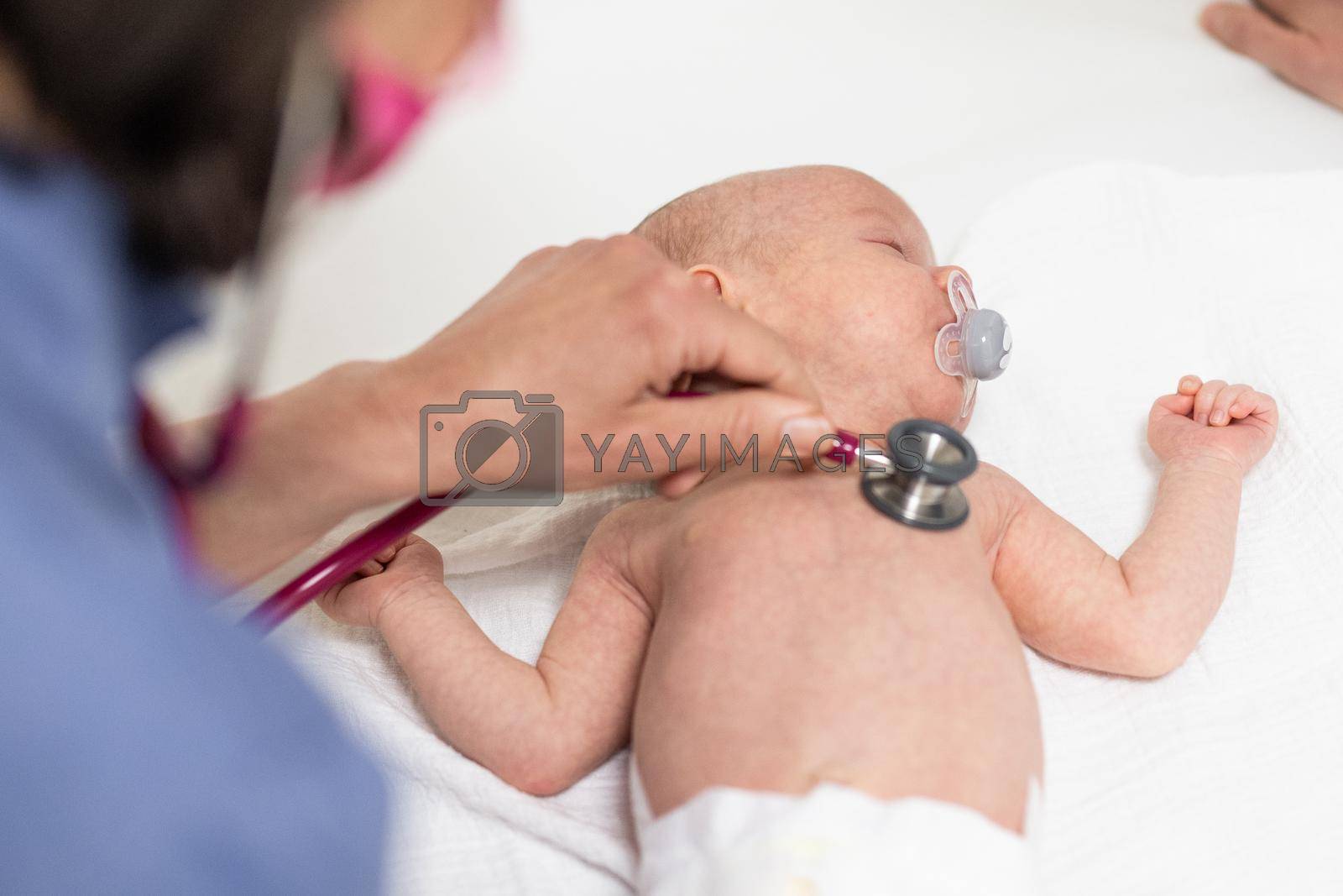 Royalty free image of Baby lying on his back as his doctor examines him during a standard medical checkup by kasto