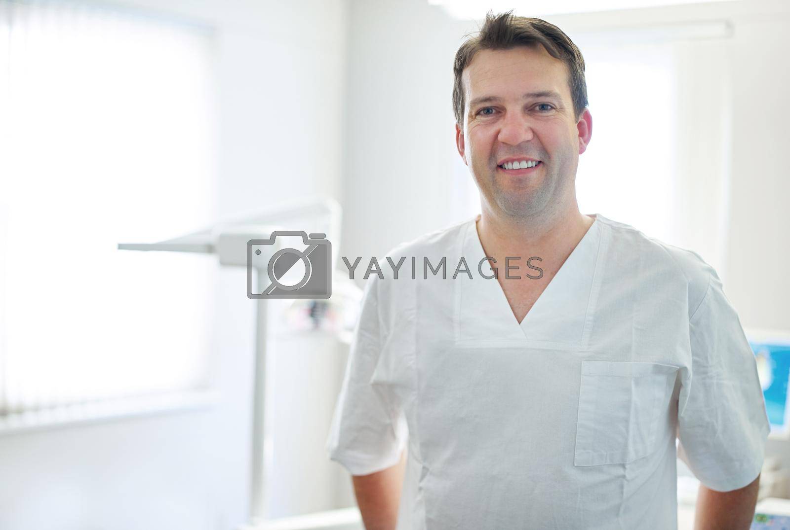 Your friendly dentist. Portrait of a male dentist standing by the dental equipment in his office