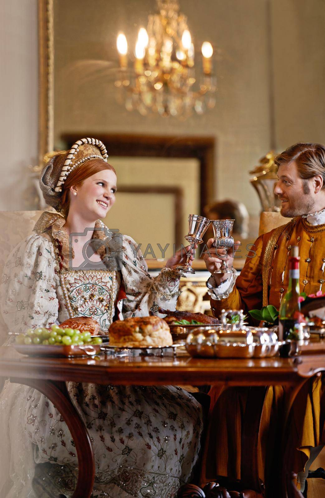 Royalty free image of Enjoying the perks of royal birth. A regal king and queen enjoying a meal together. by YuriArcurs