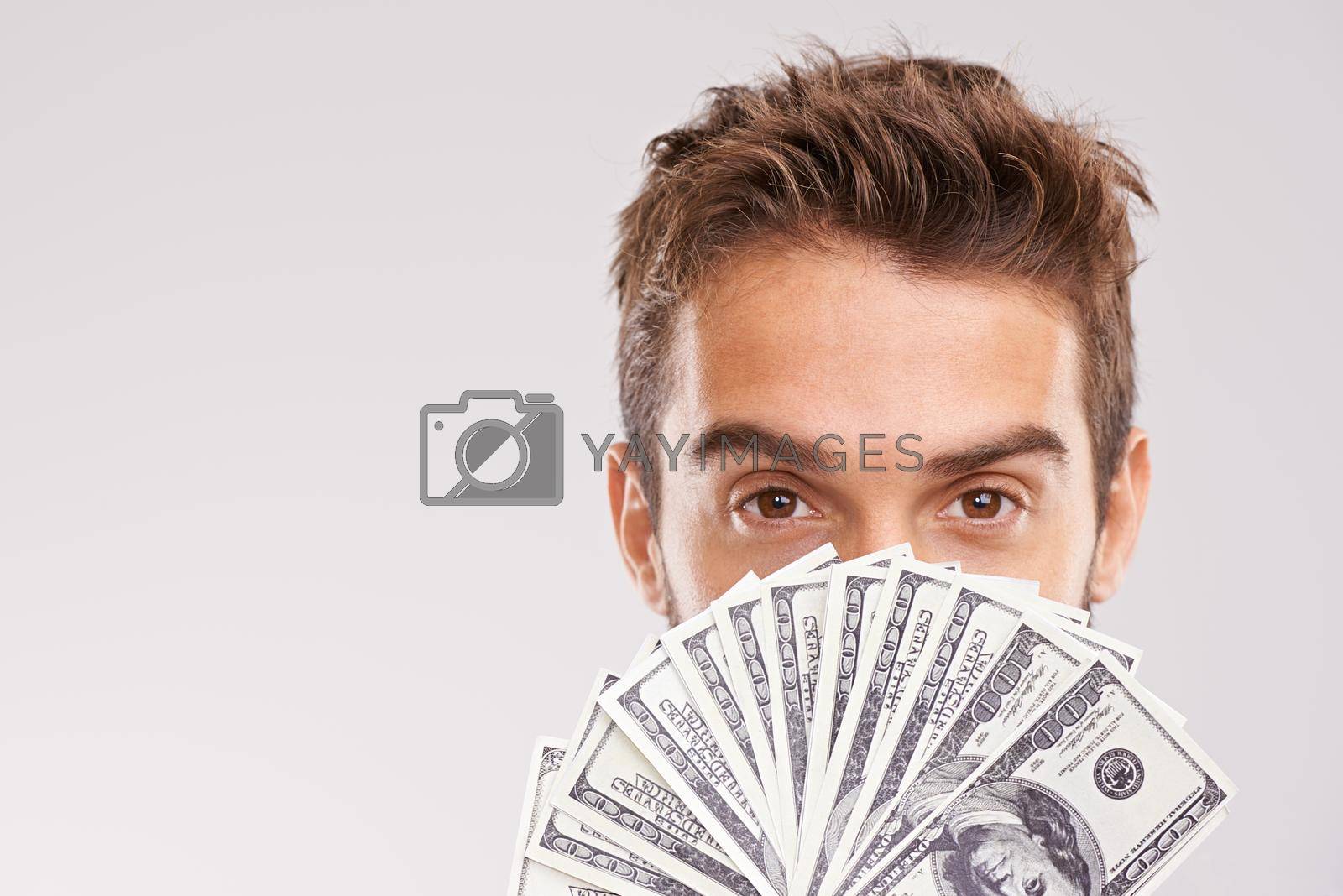 Ive got money to spare. Studio shot of a businessman holding a fan of money in front of his face
