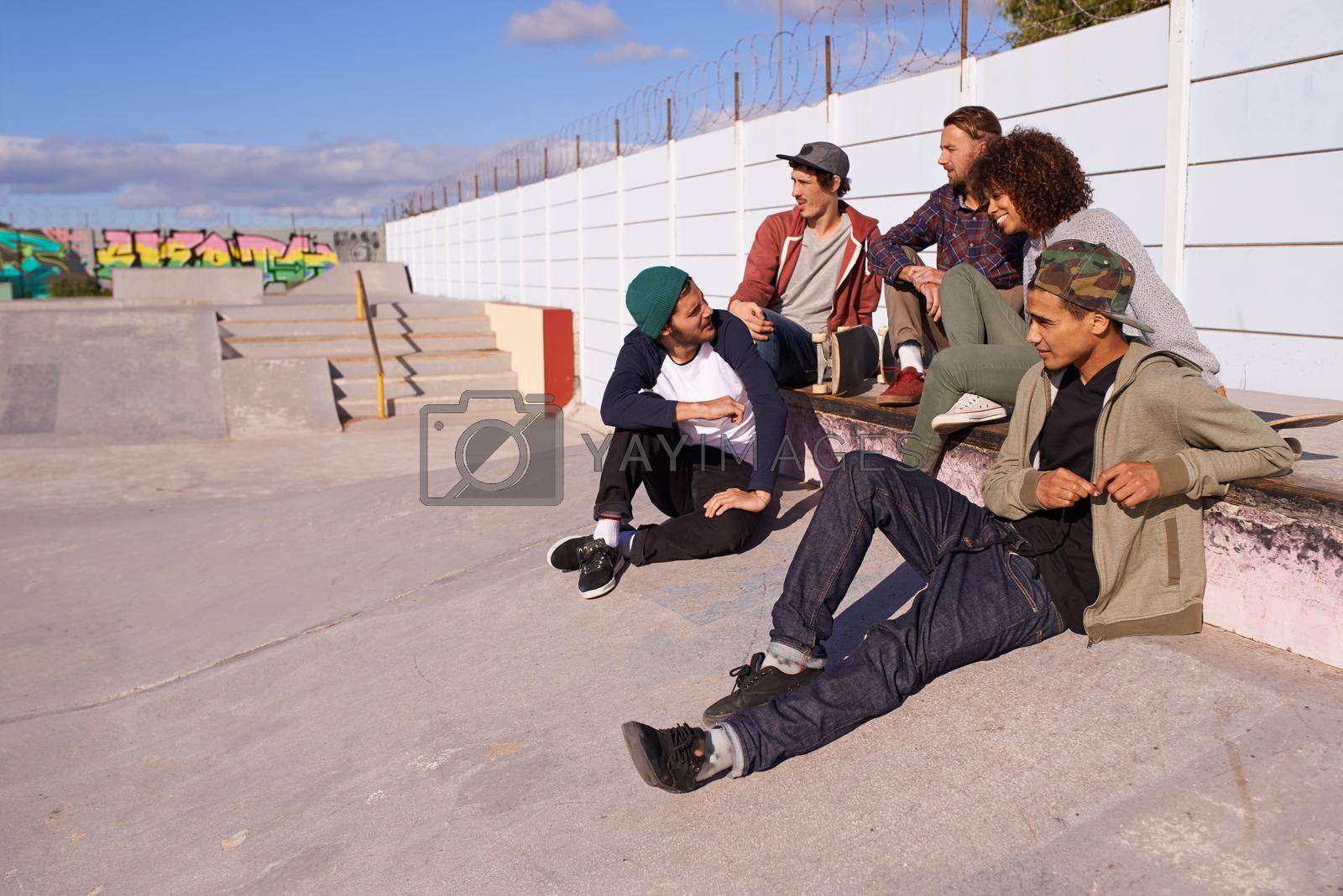 Royalty free image of Taking a break from the boards. a group of friends hanging out at a skate park. by YuriArcurs