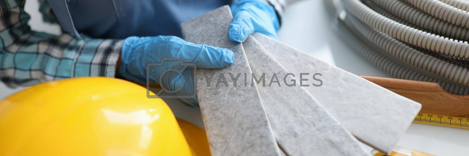 Royalty free image of Builder holding gray tiles for bathroom in workshop closeup by kuprevich