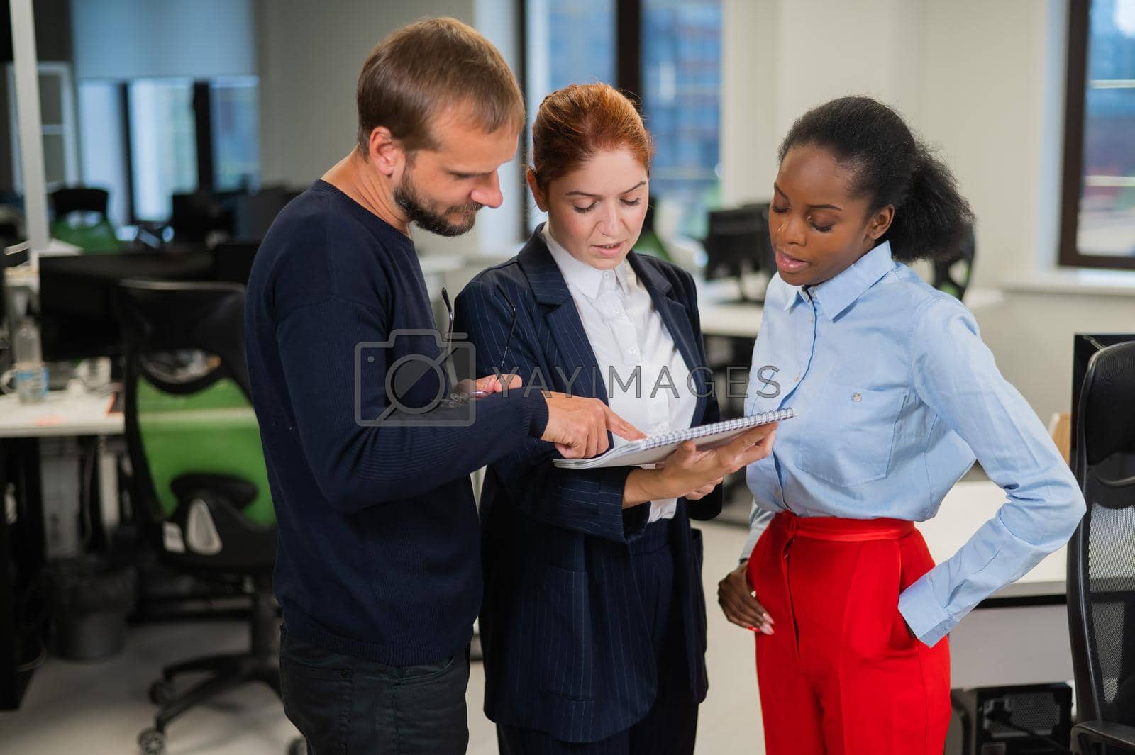 Royalty free image of Colleagues discuss work. African young woman, caucasian man and red-haired caucasian woman communicate in the office. by mrwed54