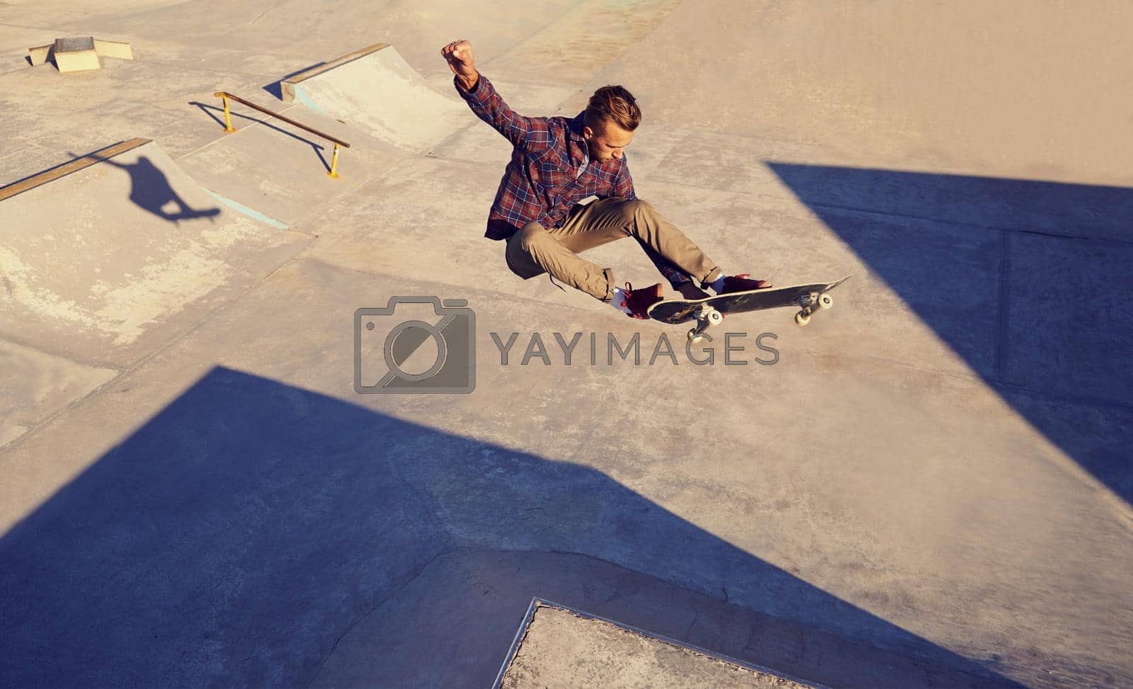 Royalty free image of But can he land it...A young man doing tricks on his skateboard at the skate park. by YuriArcurs