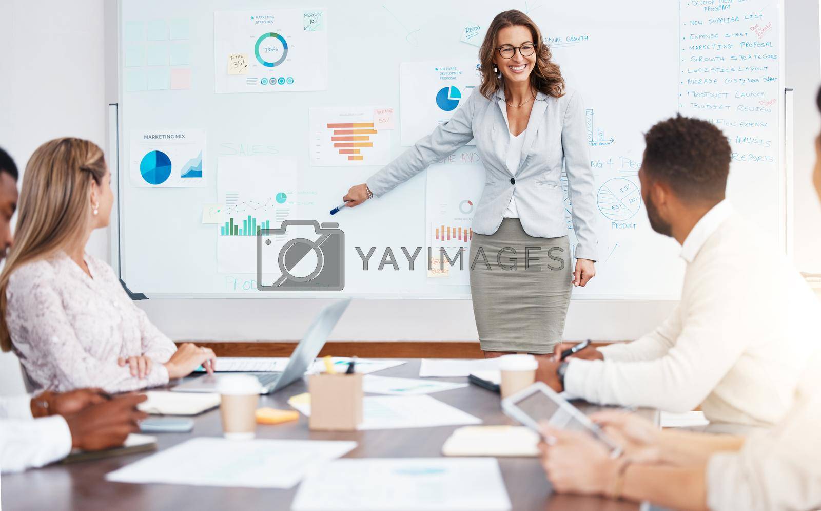 Royalty free image of Business manager doing a corporate presentation to a team in the company conference room. Business meeting with graphs, charts and data paperwork for planning a management strategy on a project. by YuriArcurs