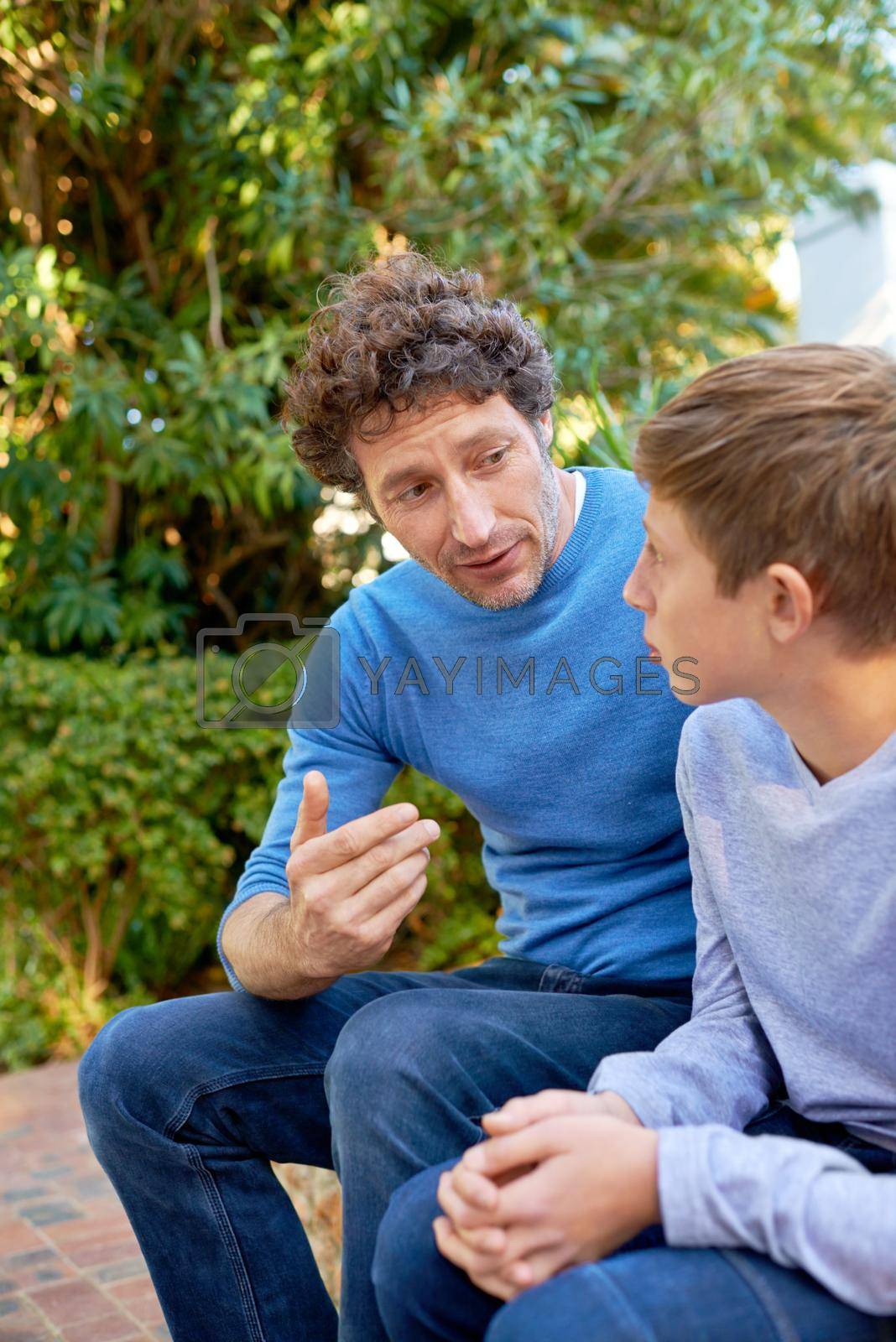 Royalty free image of This is what you should do...a father and son having a heart to heart in the backyard. by YuriArcurs