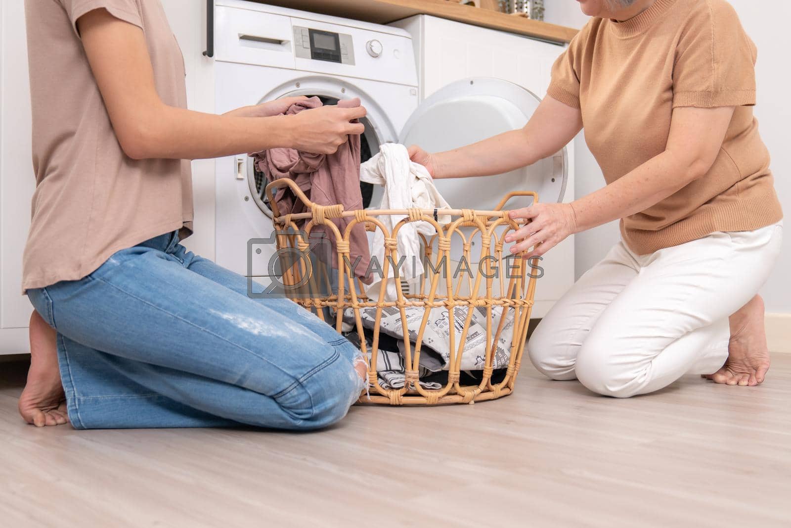Royalty free image of Contented daughter and mother in the household washing room working together. by biancoblue