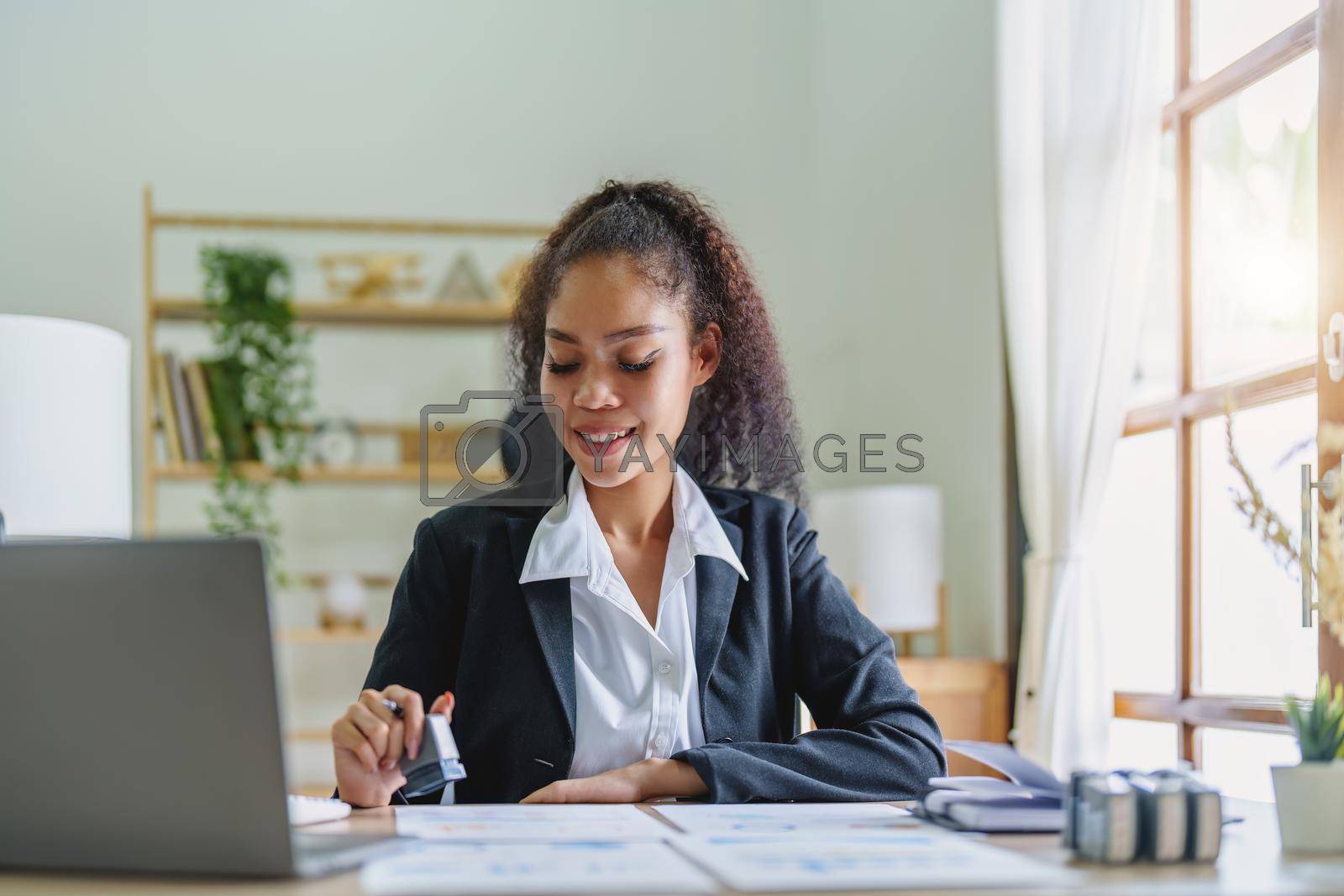 Royalty free image of African Americans businesswoman stamping budget approval on financial documents by Manastrong