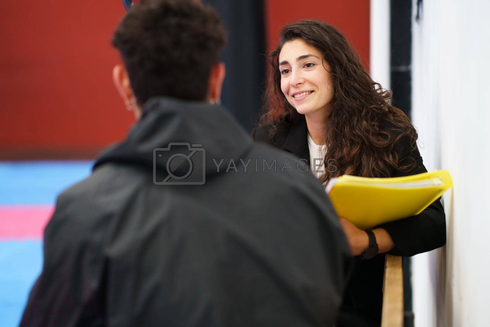 Royalty free image of Friendly female counselor listening to sportsman in gym by javiindy