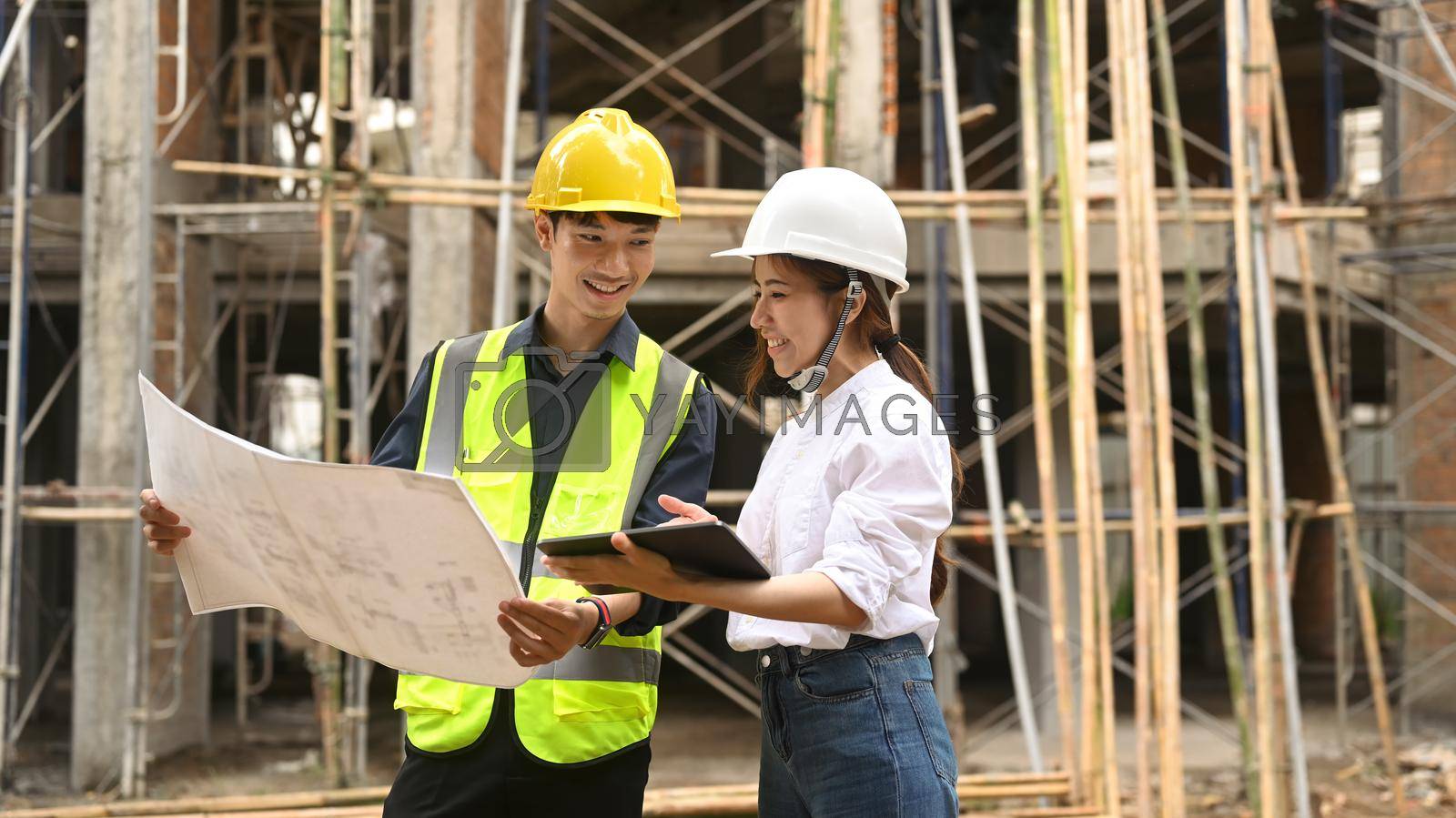 Royalty free image of Team of young Architect people looking at blueprints, inspecting industrial building construction site by prathanchorruangsak