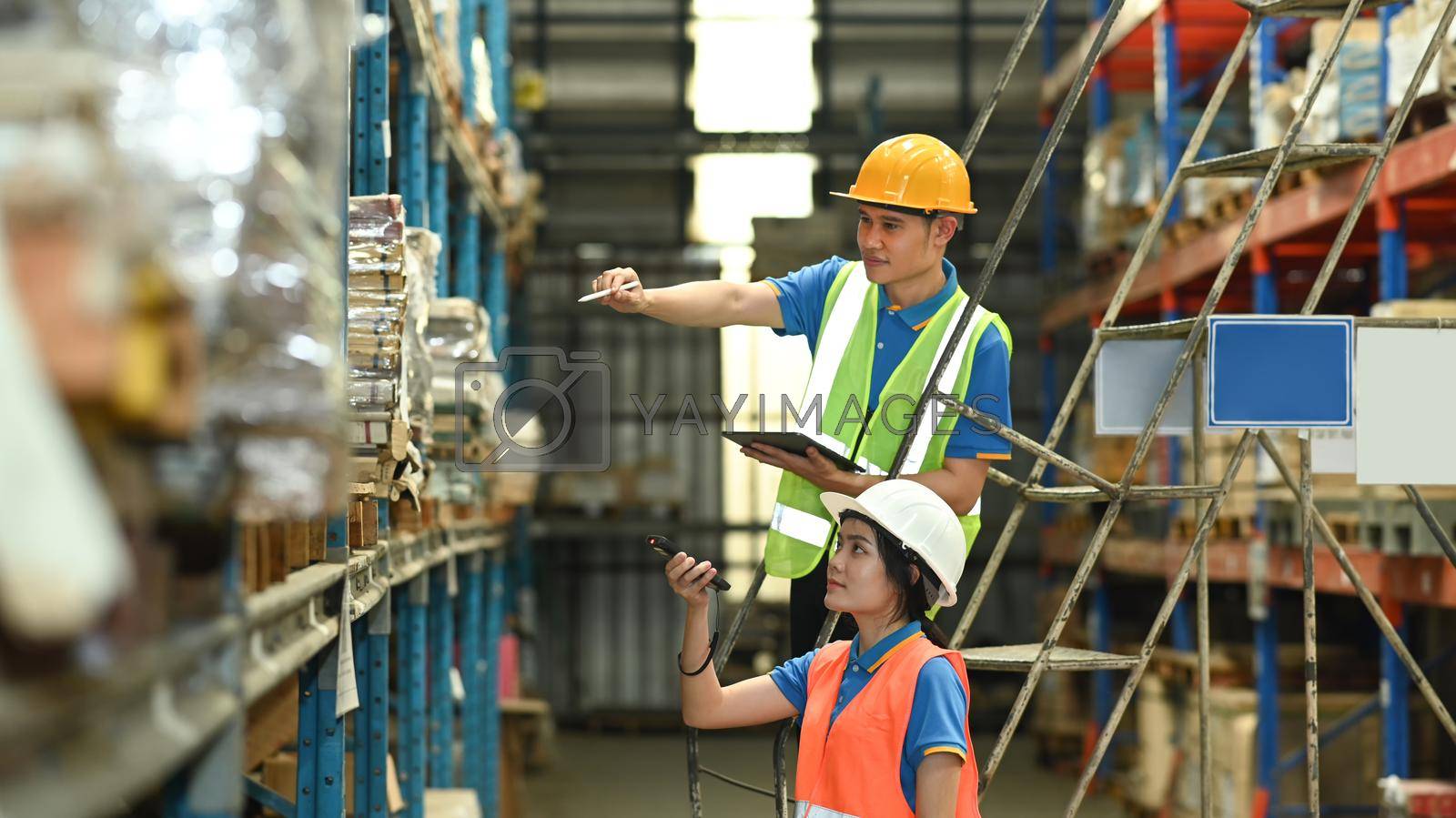 Royalty free image of Warehouse workers checking inventory boxes with barcode scanner on shelf in a large warehouse by prathanchorruangsak