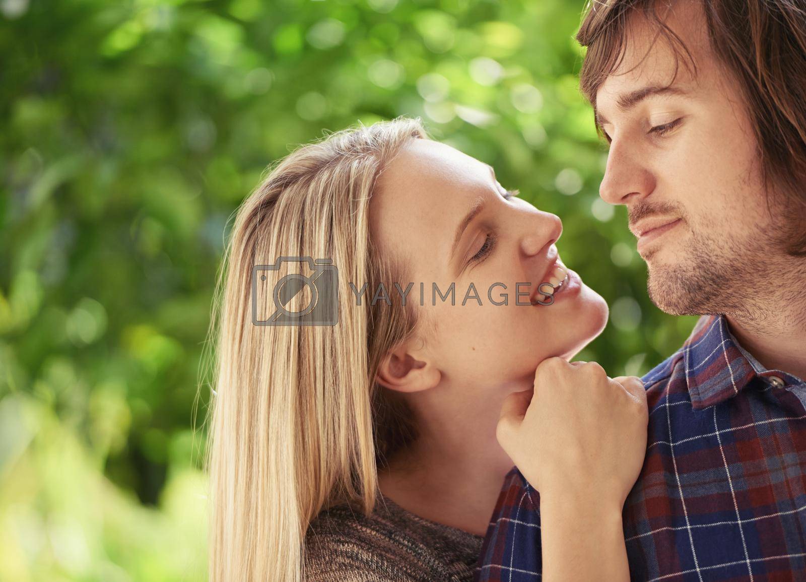 Royalty free image of Young and filled with passion. Portrait of a smiling young couple hugging each other in the park. by YuriArcurs