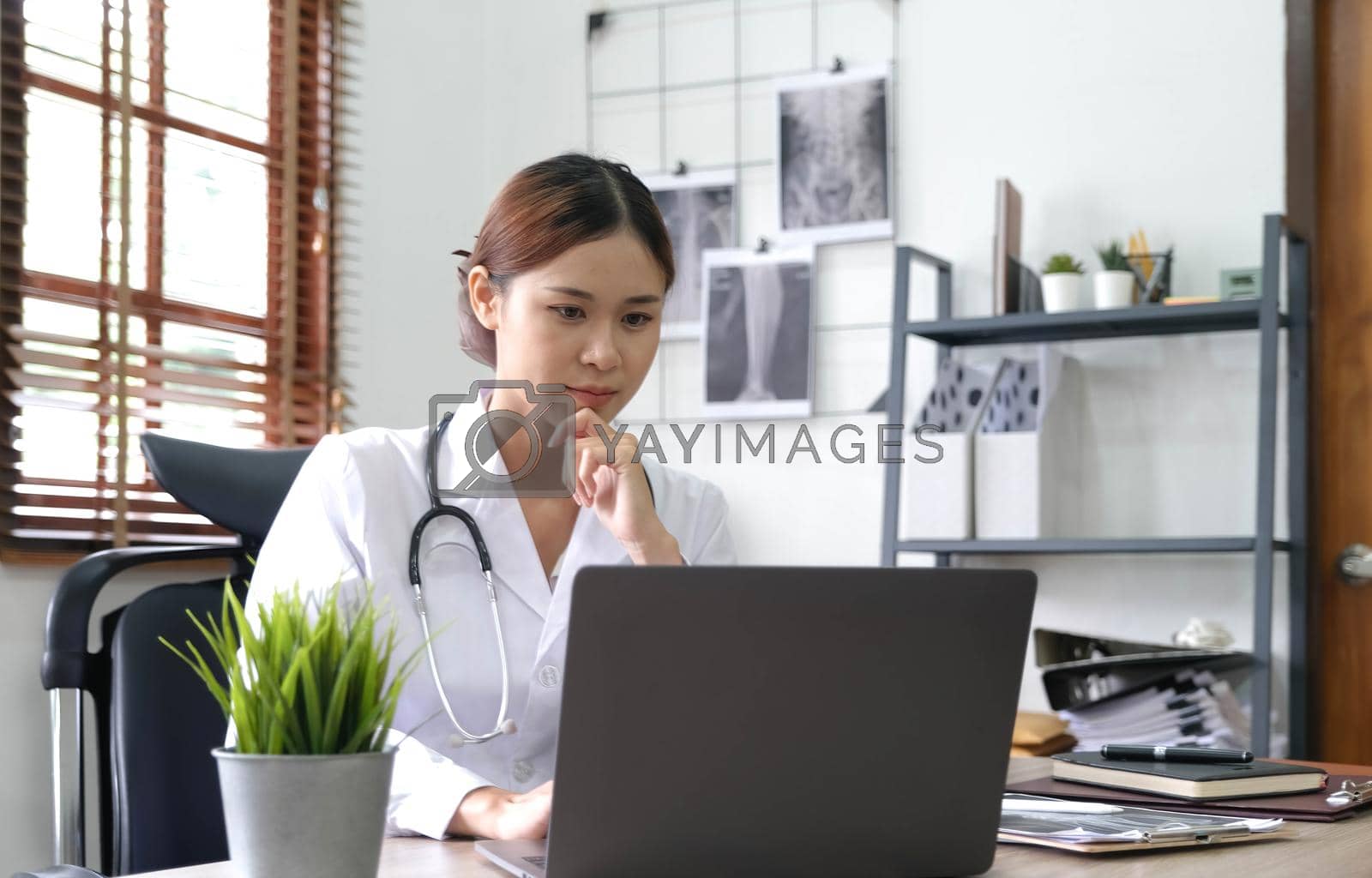 Royalty free image of Portrait happy asian woman doctor, Telemedicine concept. Asian female doctor talking with patient using laptop online video webinar consultation while sitting in clinic office by wichayada