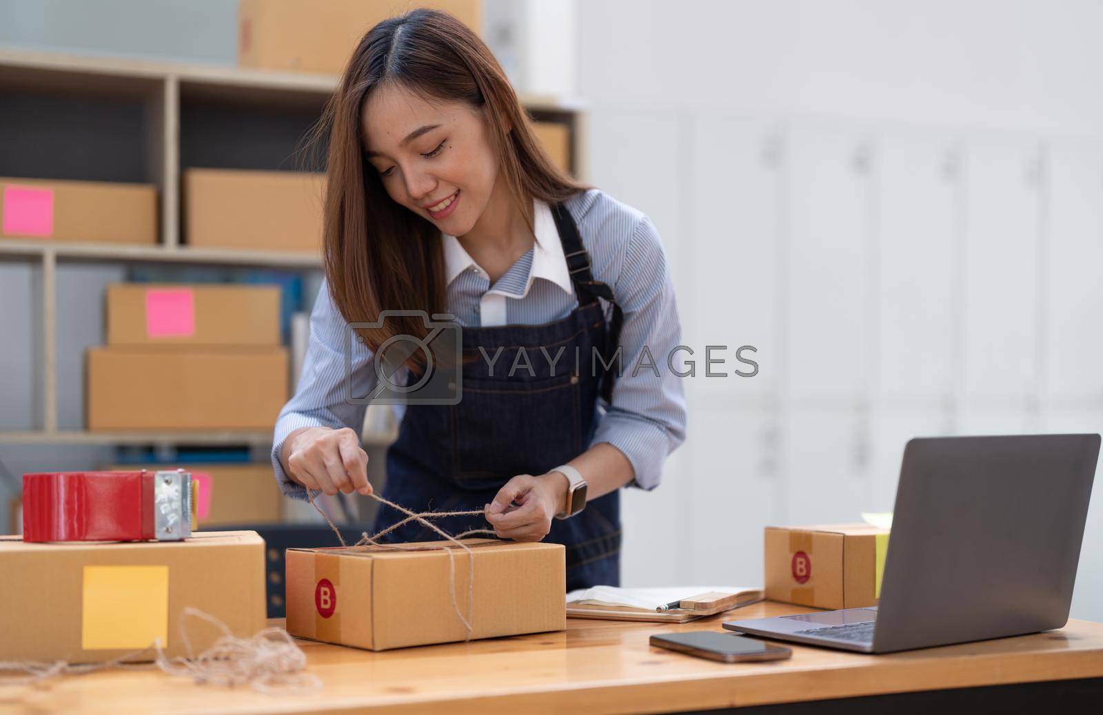 Royalty free image of Young small business owner packing deliveries in modern office and storage space by nateemee