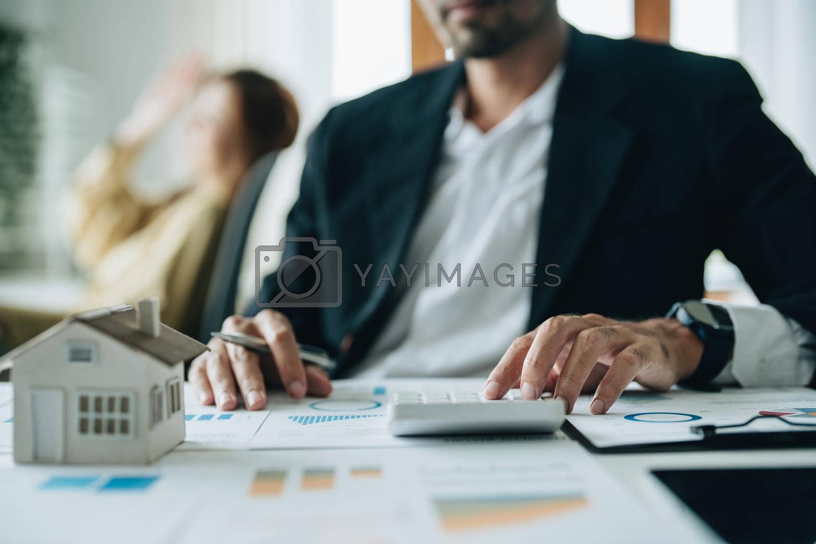 Royalty free image of Bank loan workers are using calculators to calculate home loan interest rates for customers to assess their investment capabilities using key documents at working by Manastrong