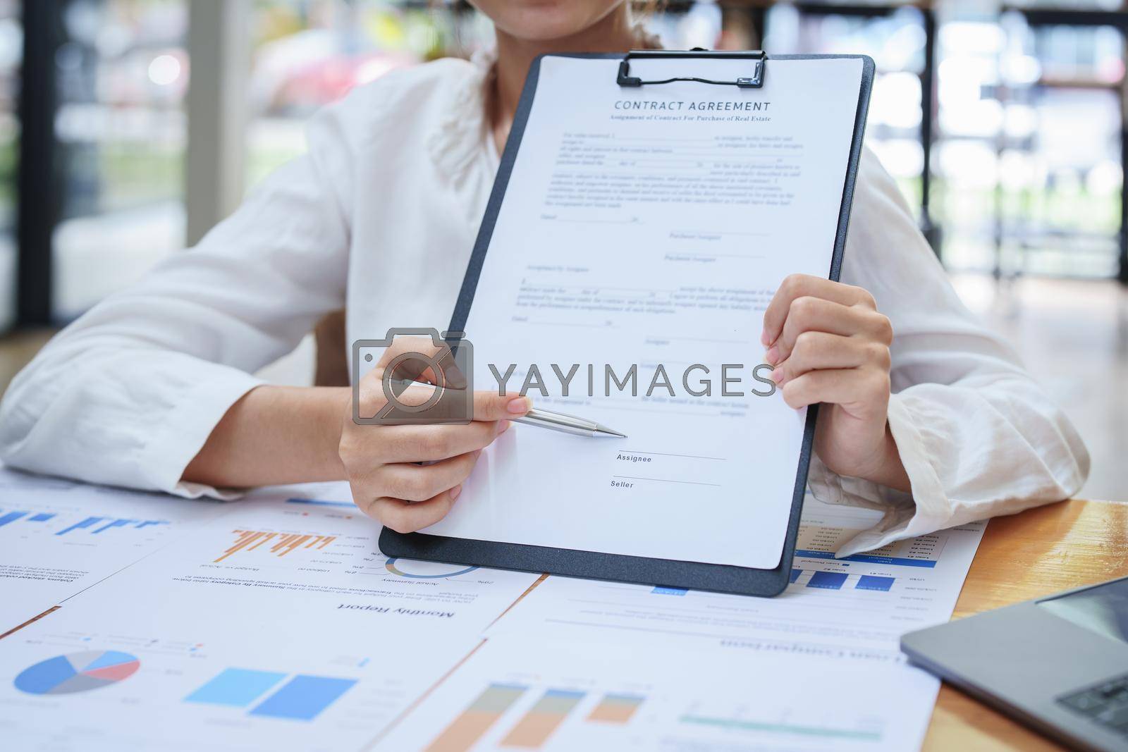 Royalty free image of female business owner reading important documents before signing by Manastrong