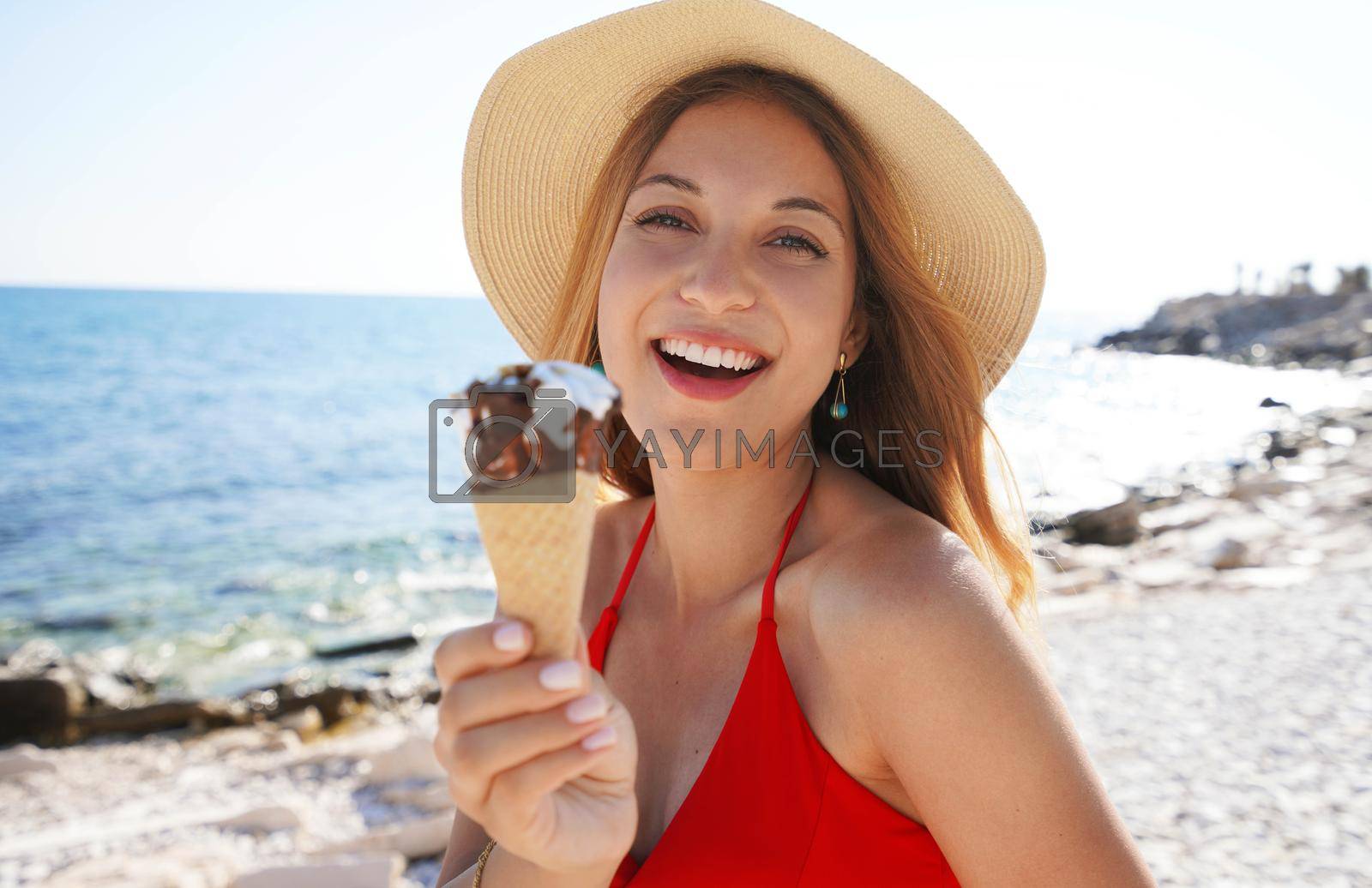 Royalty free image of Close-up of beautiful bikini woman with hat holding eating ice cream cone italian gelato on the beach on summer by sergio_monti