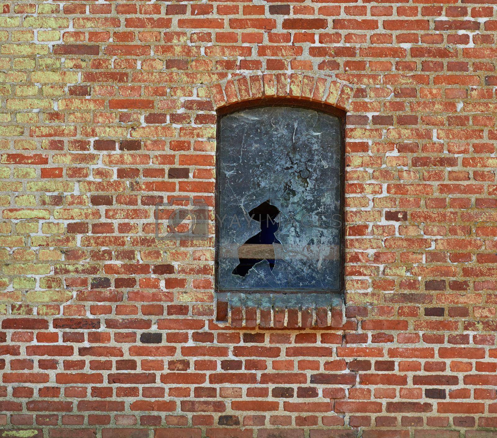 Royalty free image of Broken window on a brick building. A broken window on an abandoned building. by YuriArcurs
