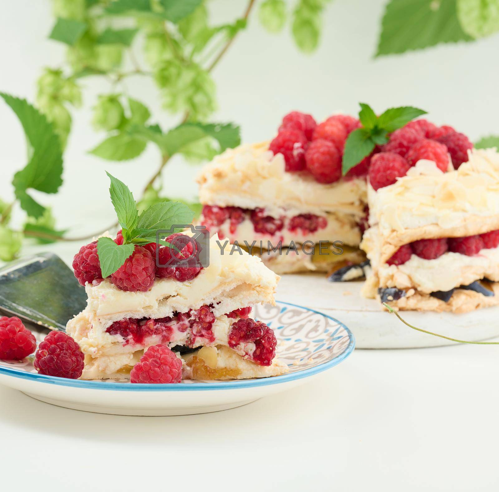 Royalty free image of Round meringue pie with fresh raspberries on a white background, Pavlova dessert by ndanko