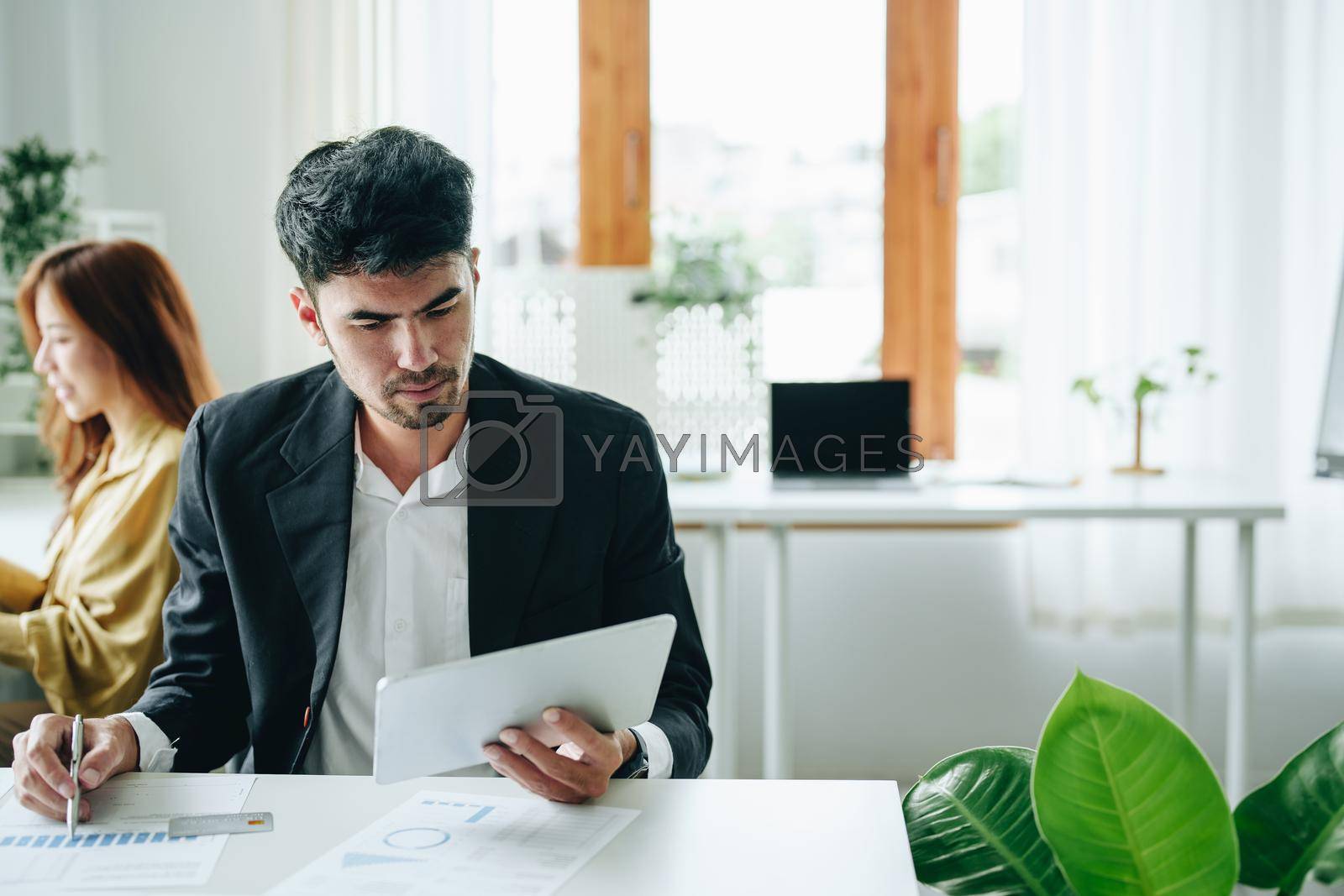 Royalty free image of Male business owners use tablets to monitor financial budgets to plan risk management and investments by Manastrong