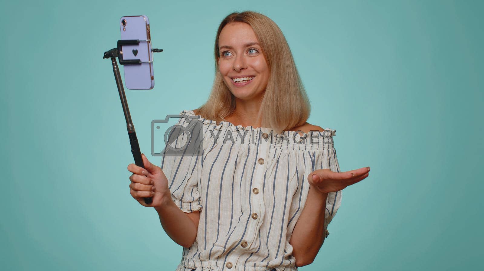 Royalty free image of Girl blogger take selfie on mobile phone selfie stick communicate video call online with subscribers by efuror