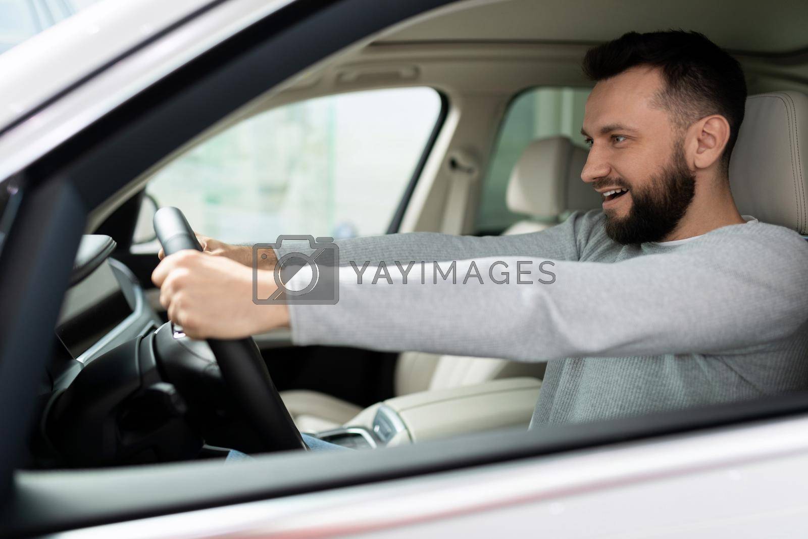 Royalty free image of novice driver behind the wheel of a new car looks ahead with a smile by TRMK