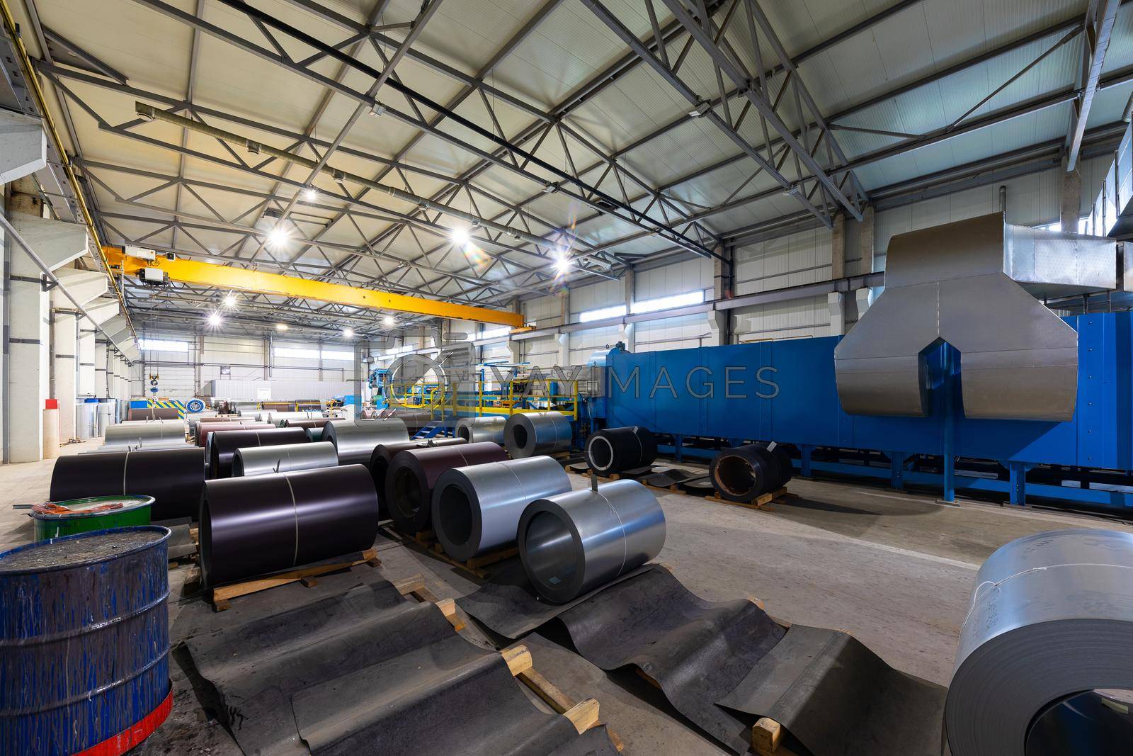 Royalty free image of Photo of steel roofing forming machine. Industrial machine for metal sheet roof coils cut. Factory and plant background by TRMK