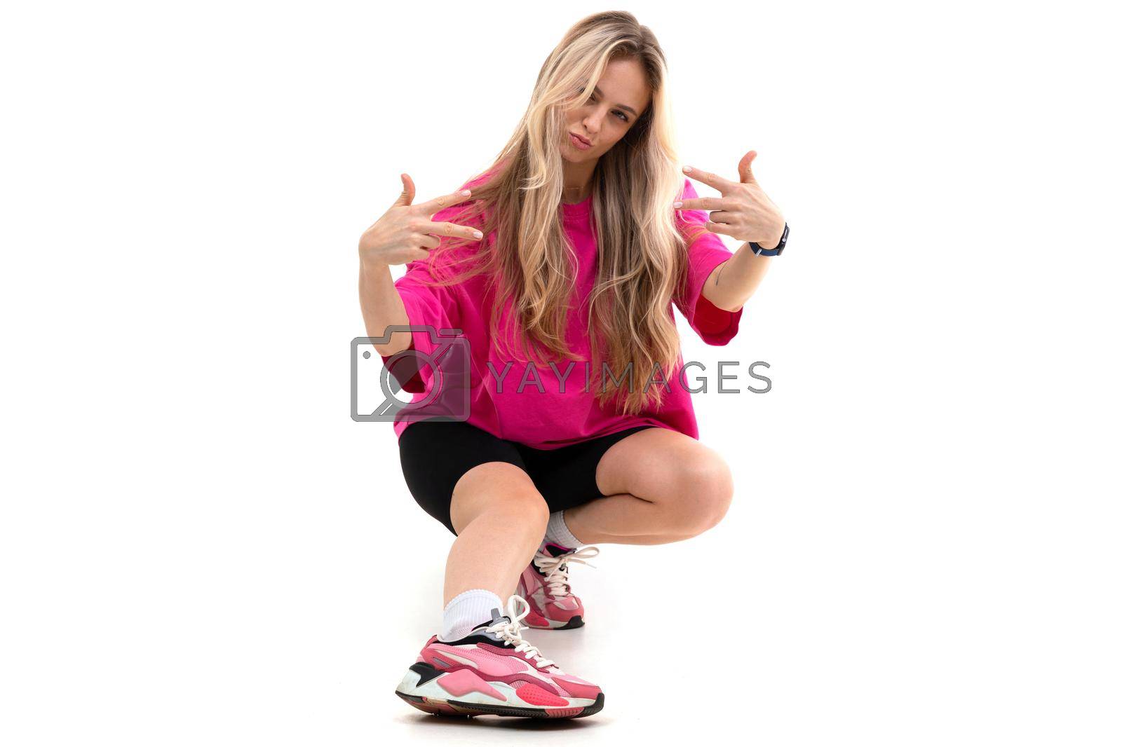 Royalty free image of woman on a white background in sportswear sits showing her fingers cool by TRMK