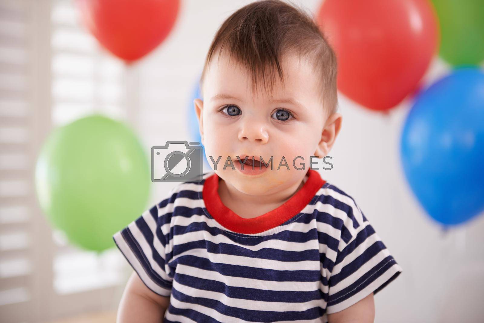 Royalty free image of Looking smart on his special day. a baby boy sitting at home with balloons in the background. by YuriArcurs