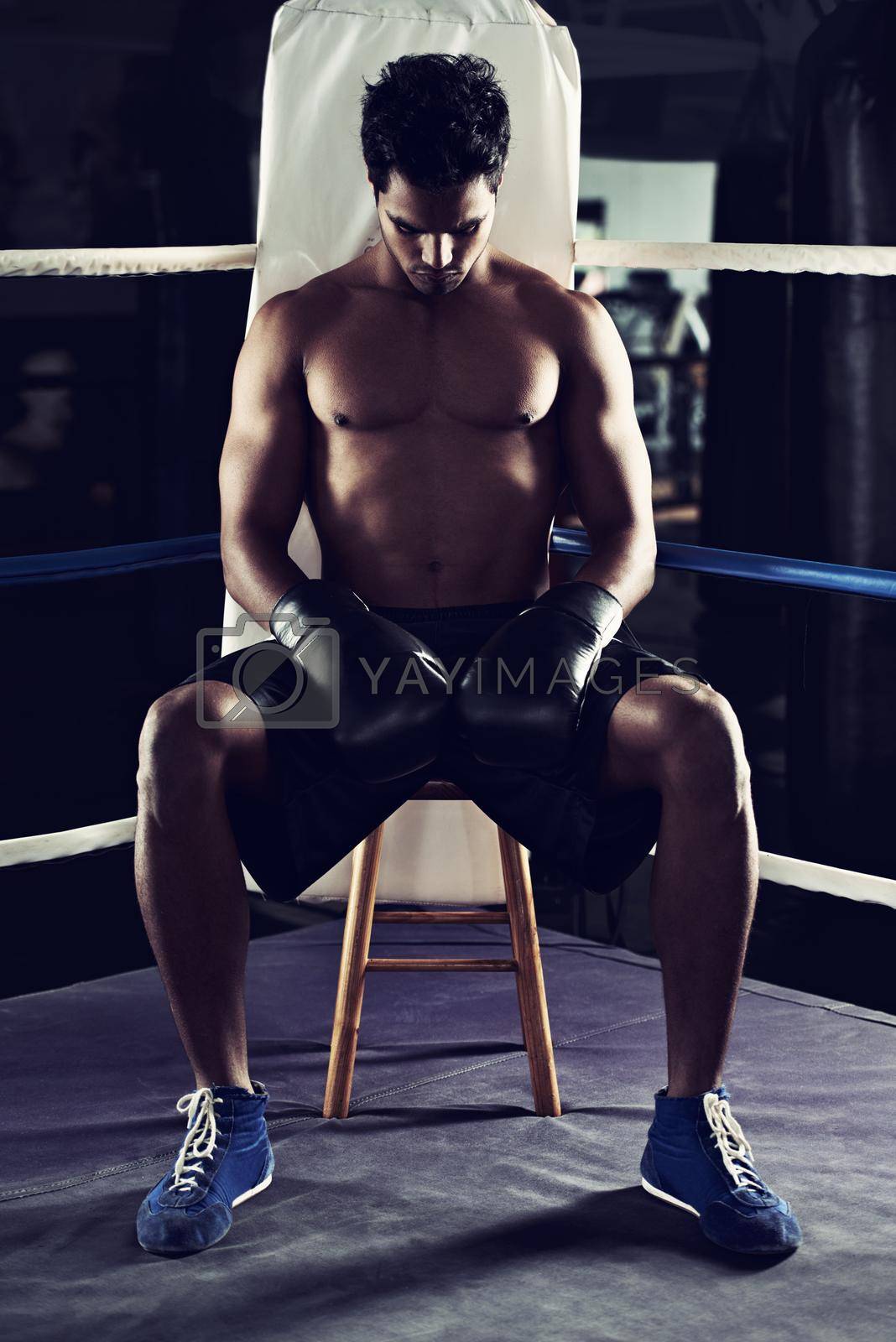 Royalty free image of Hes found his place in the boxing ring. a young male boxer sitting in a corner of a boxing ring. by YuriArcurs