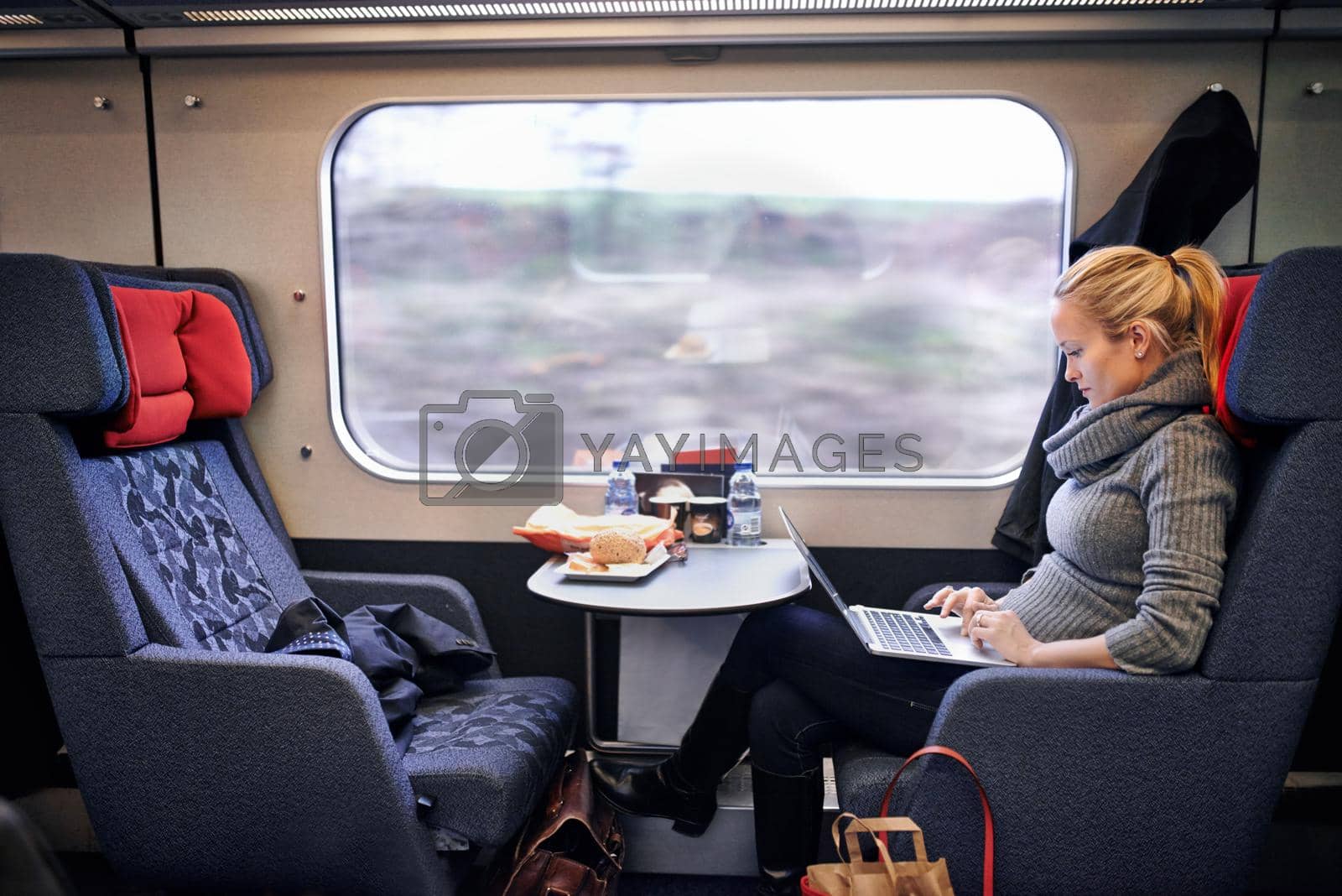Royalty free image of I have time to get some work done. an attractive young woman traveling by train. by YuriArcurs