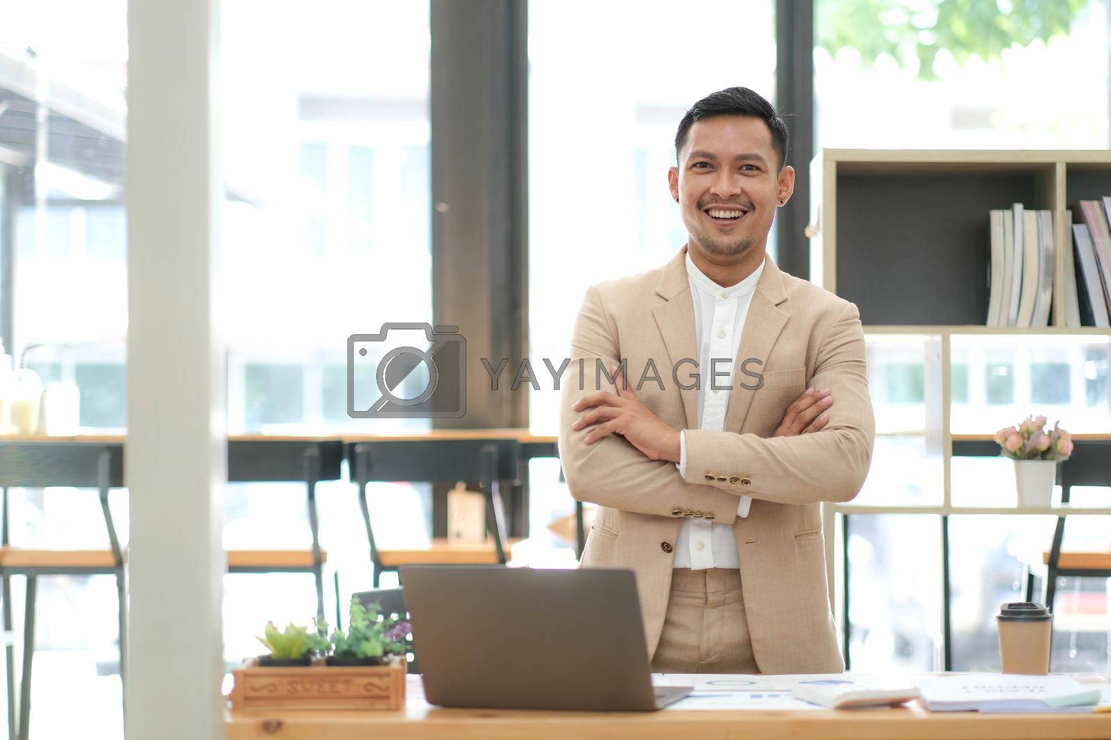 Asian businessman standing by his desk in office.