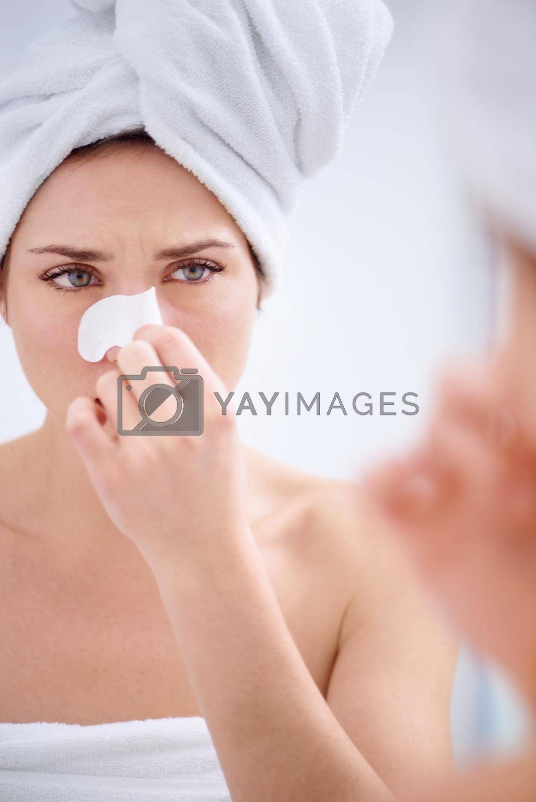 Royalty free image of Removing blackheads in one quick pluck. A young woman with a nose strip on. by YuriArcurs