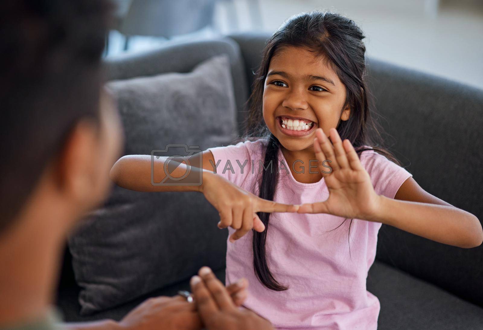 Royalty free image of Child, sign language and learning to communicate with deaf girl or parent while making fingers and showing visual symbols at home. Happy kid with hearing disability or loss sitting with a tutor by YuriArcurs