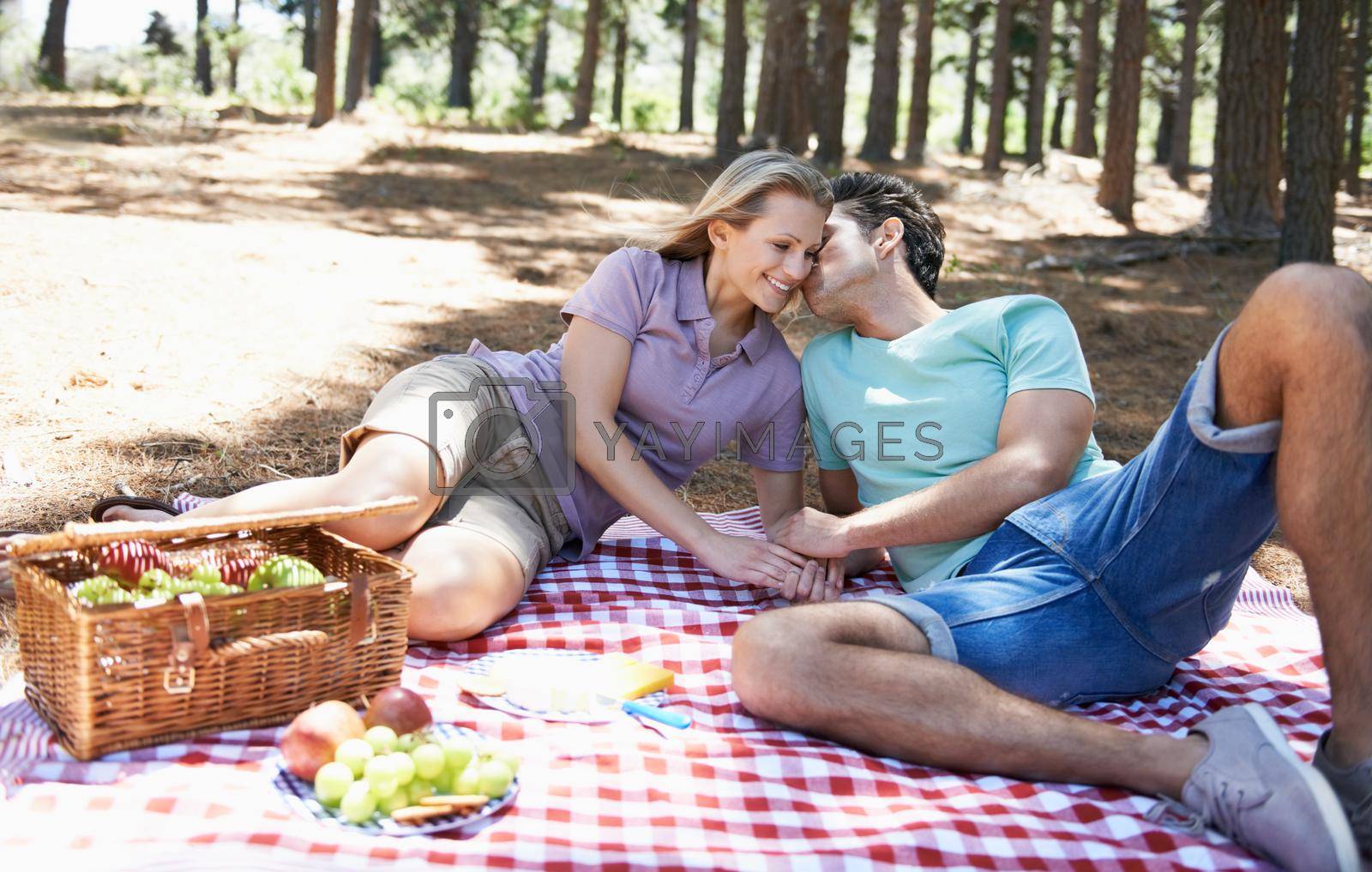 Royalty free image of Basking in the romance. A happy young couple showing each other affection while having a picnic in the forest. by YuriArcurs