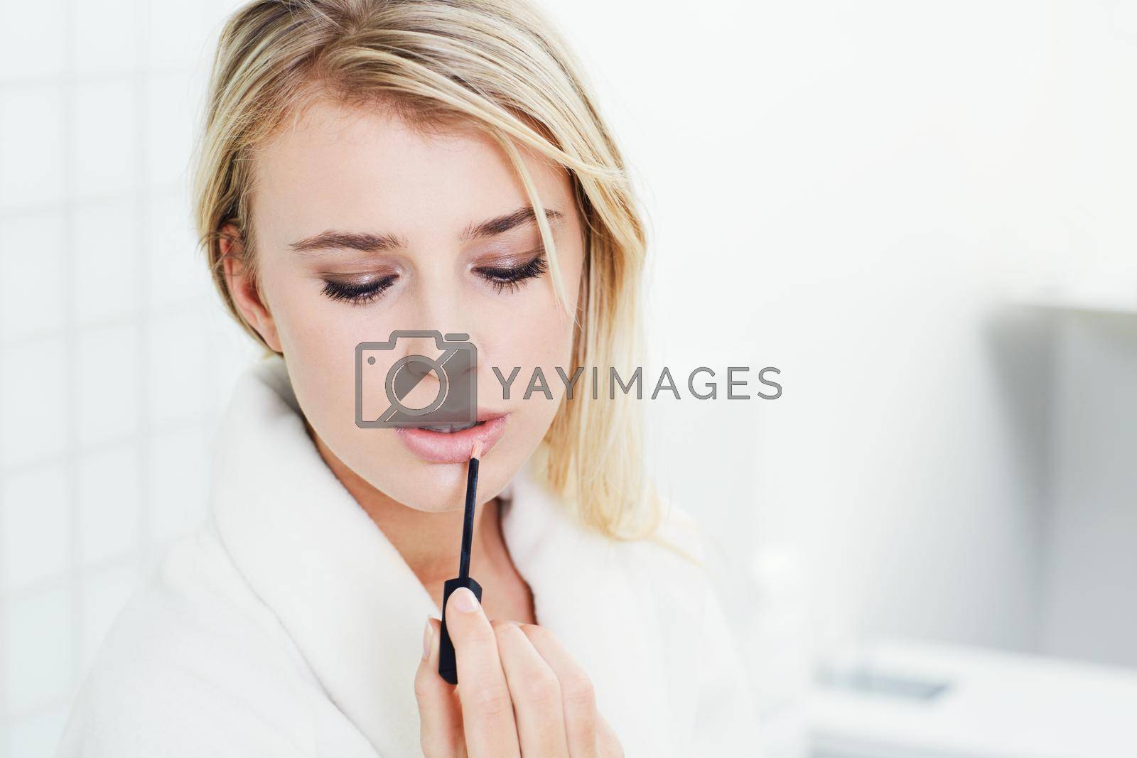 Royalty free image of Hell want to kiss her with this lipgloss. A beautiful young woman applying lipgloss. by YuriArcurs