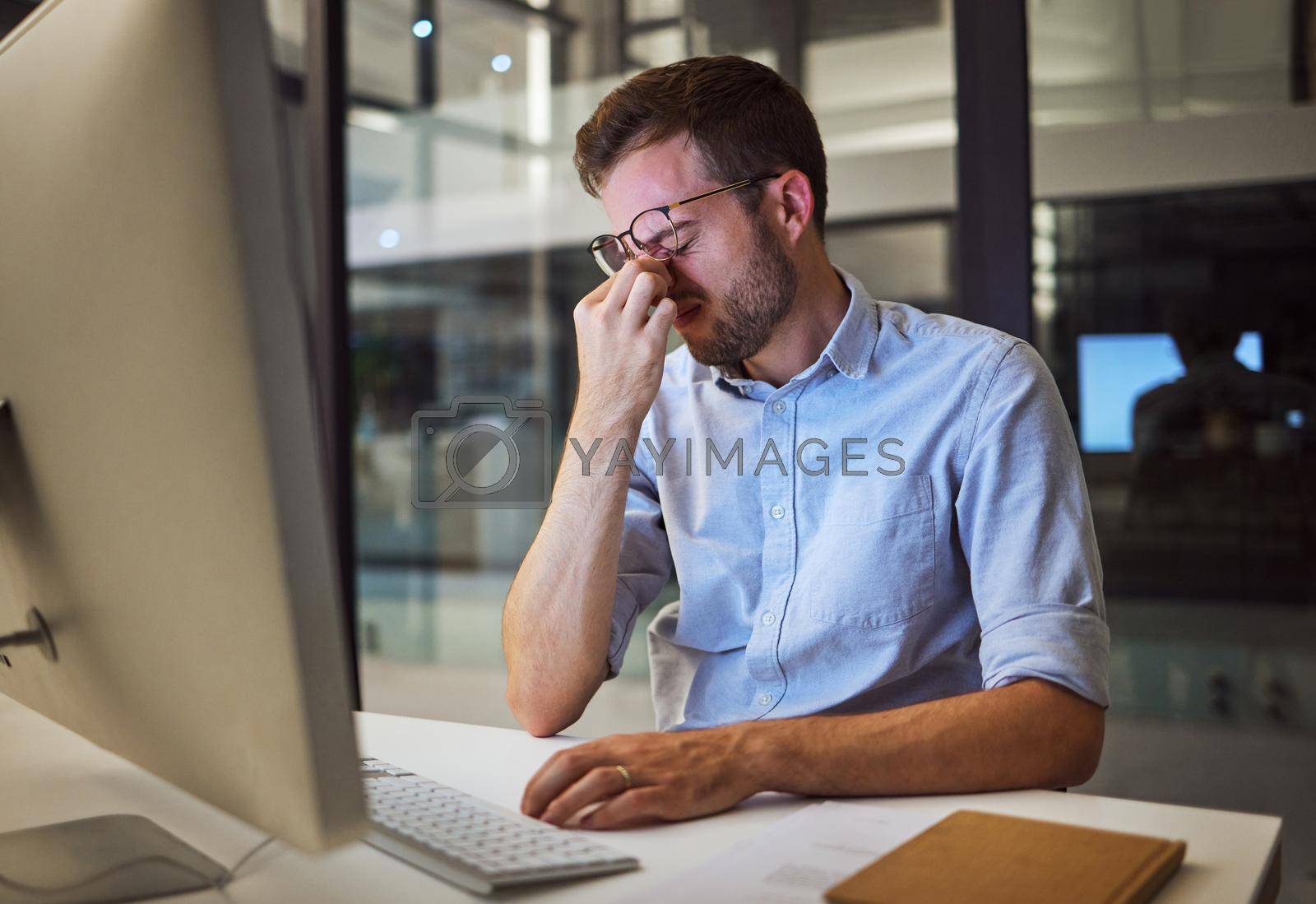 Royalty free image of Night business, stress and tired man sitting at his computer desk with headache, depression and burnout from work pressure. Stressed, mental health and depressed male working late in his office by YuriArcurs
