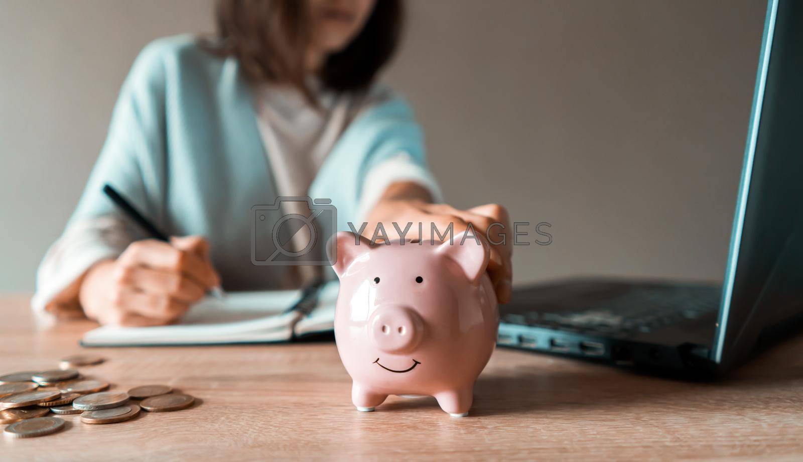 Royalty free image of Girl makes calculations, puts funds in a piggy bank. by africapink