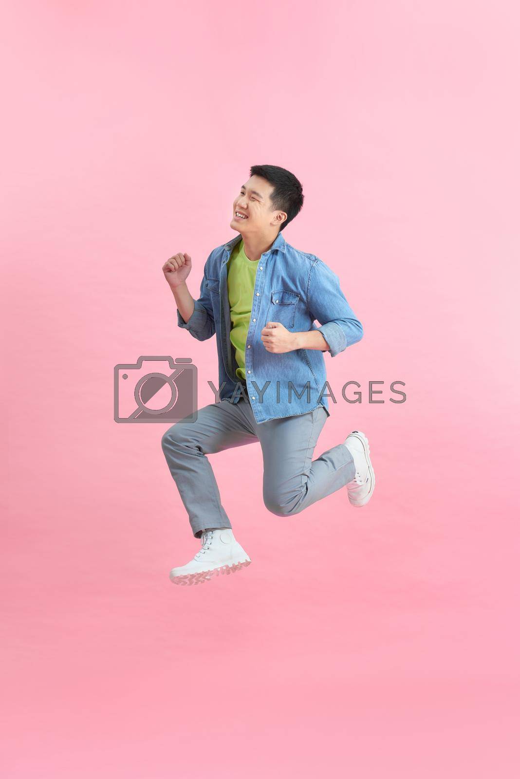 Royalty free image of Energetic happy young Asian man jumping isolated in pink background by makidotvn