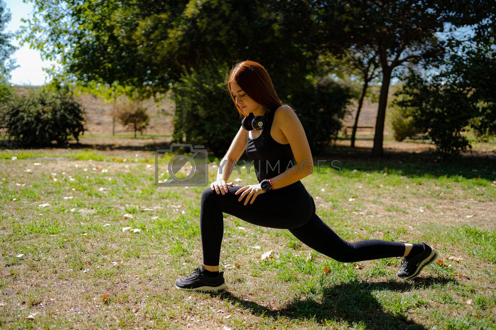 Royalty free image of Redhead fitness woman doing lunge exercises for leg muscle training. by barcielaphoto