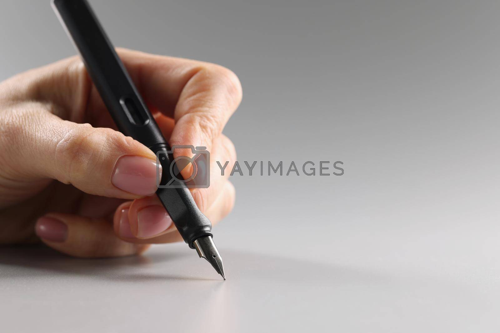 Royalty free image of Female fingers hold a black fountain pen, close-up by kuprevich
